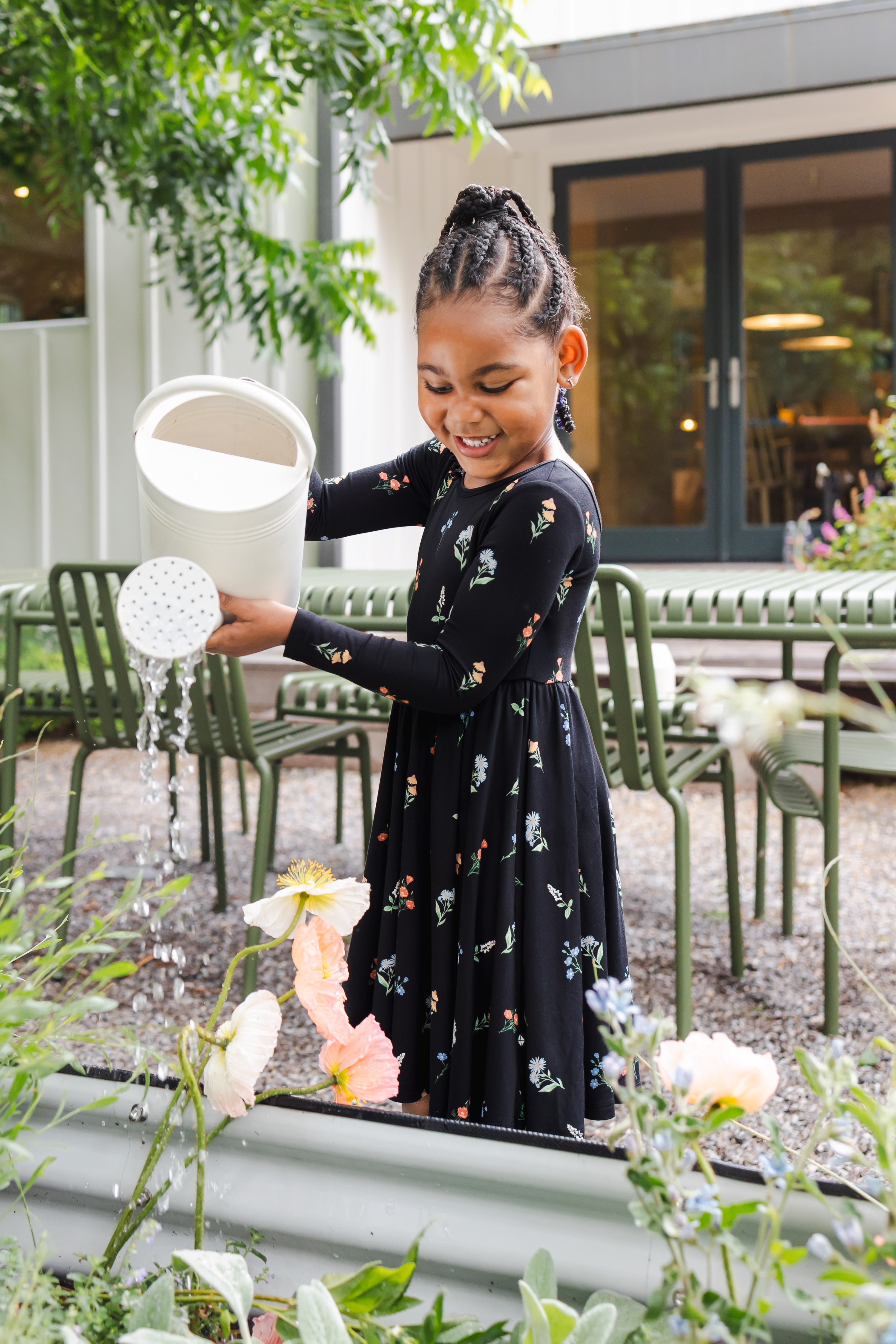 Girl watering plants outdoors wearing Long Sleeve Twirl Dress in Midnight Wildflower print