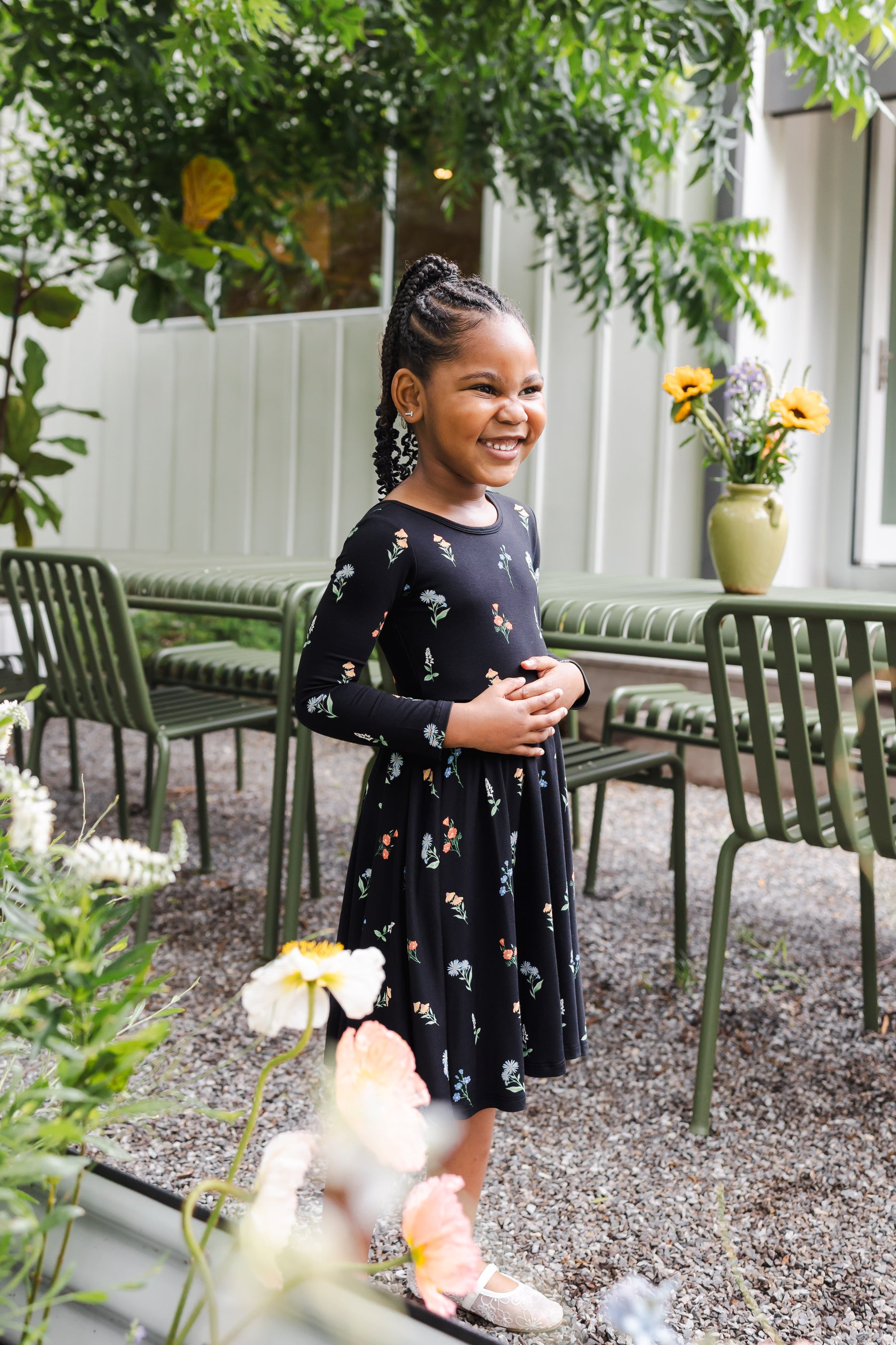 Girl standing outdoors in a garden wearing Long Sleeve Twirl Dress in Midnight Wildflower print