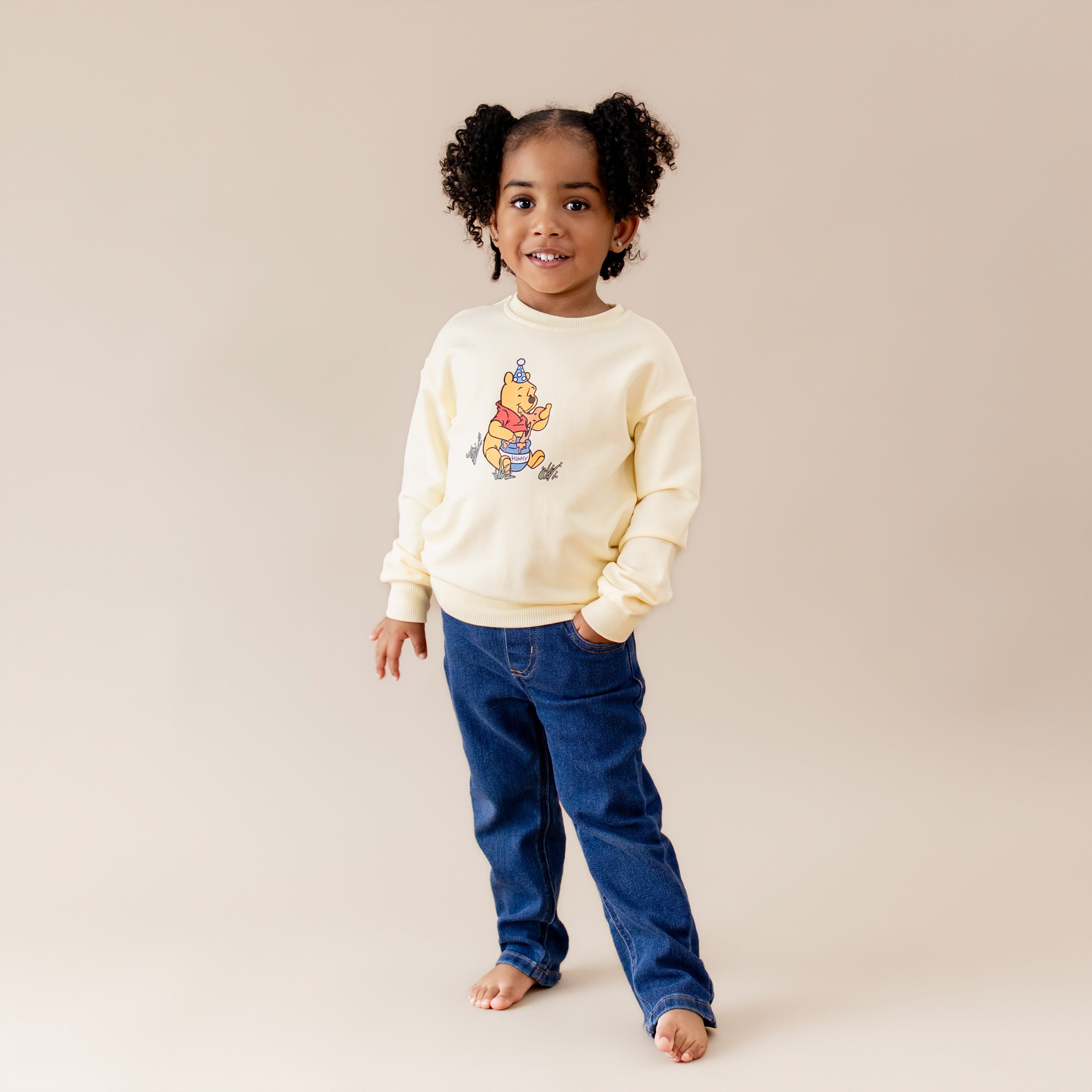 Young girl modeling the Sweatshirt in Winnie the Pooh on Chamomile paired with dark denim jeans