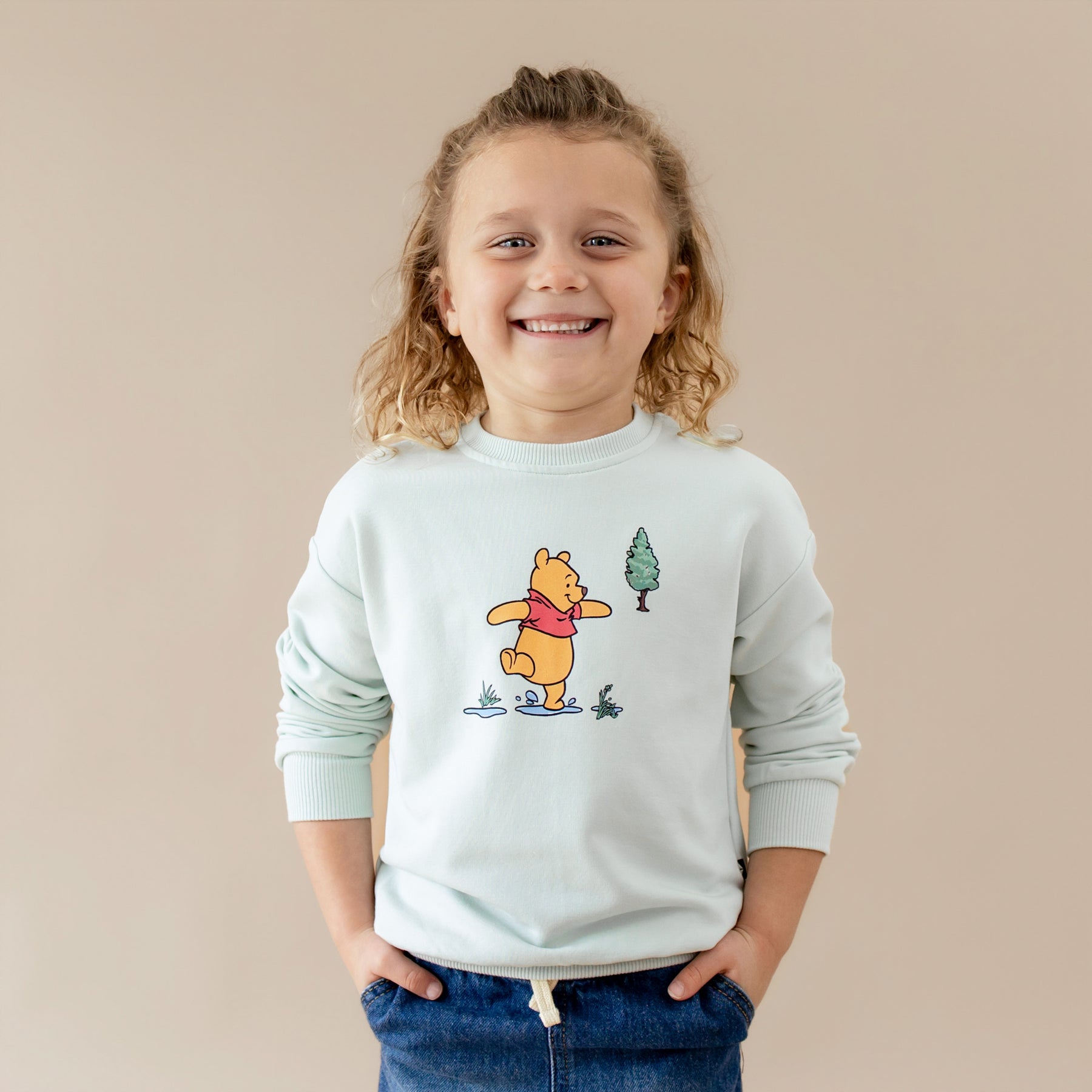 Smiling child wearing the Sweatshirt in Winnie the Pooh on Dew with their hands in he pockets of their jeans