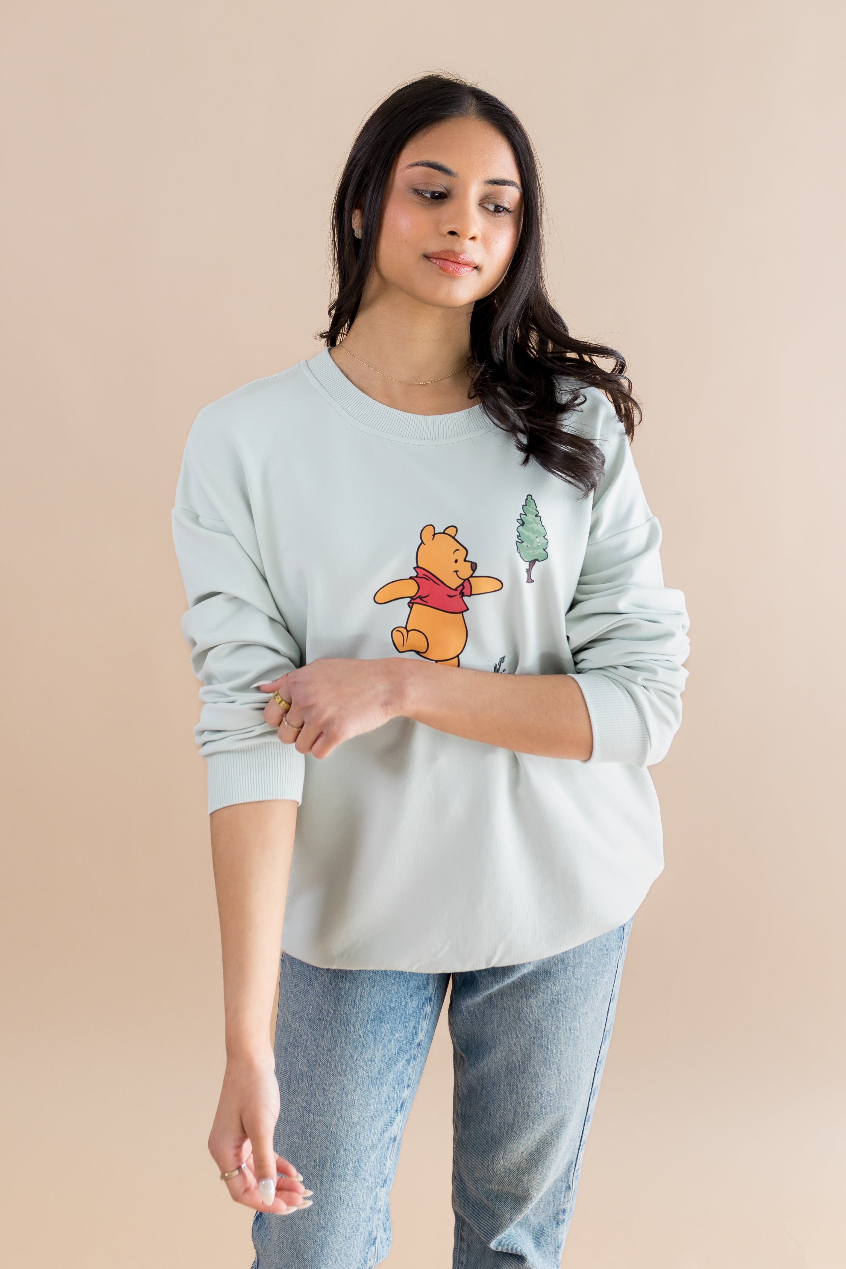Female wearing the Women's Sweatshirt in Winnie the Pooh on Dew rolling up of the sleeves on the shirt