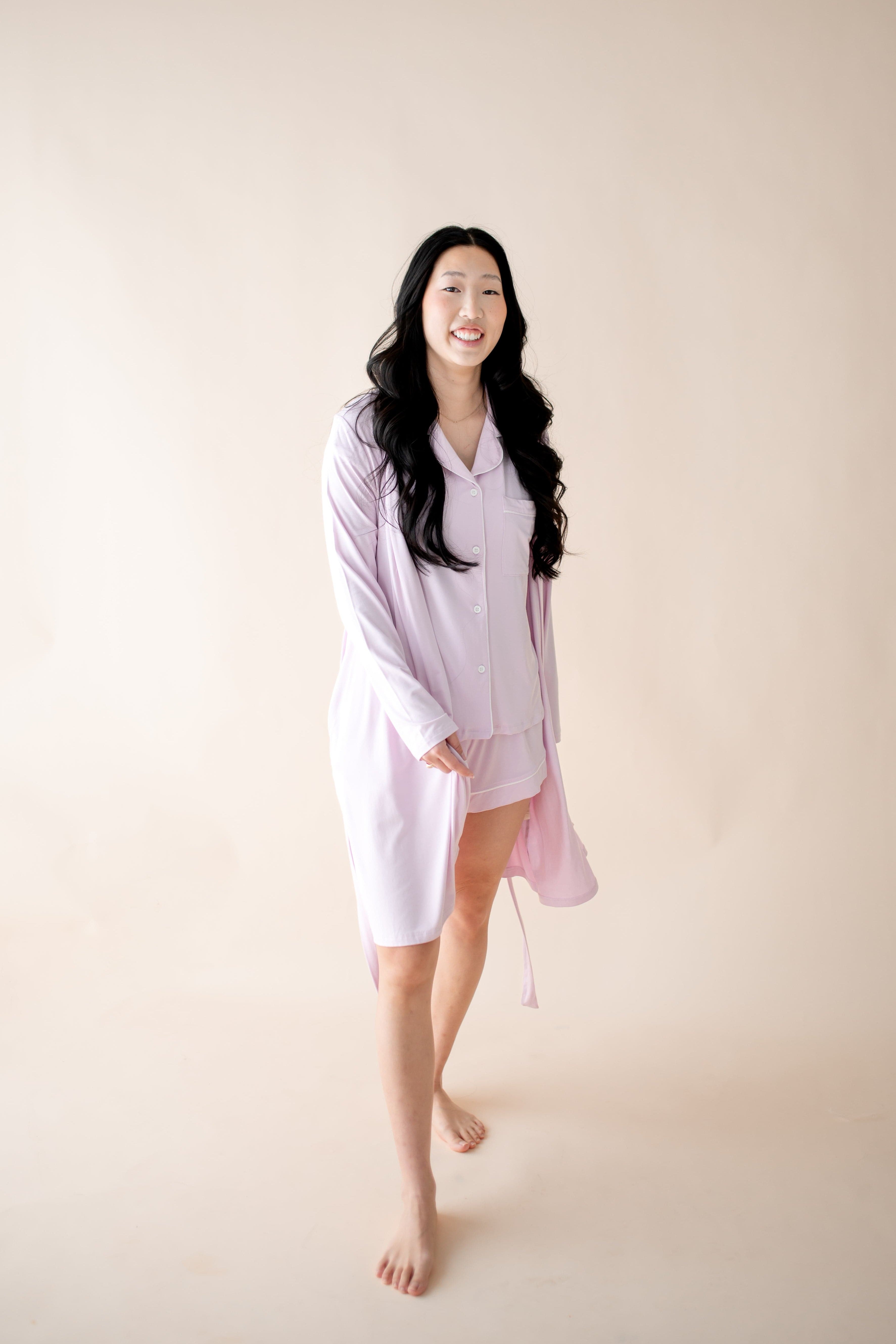 Woman wearing a light purple robe with matching PJ set against a plain background