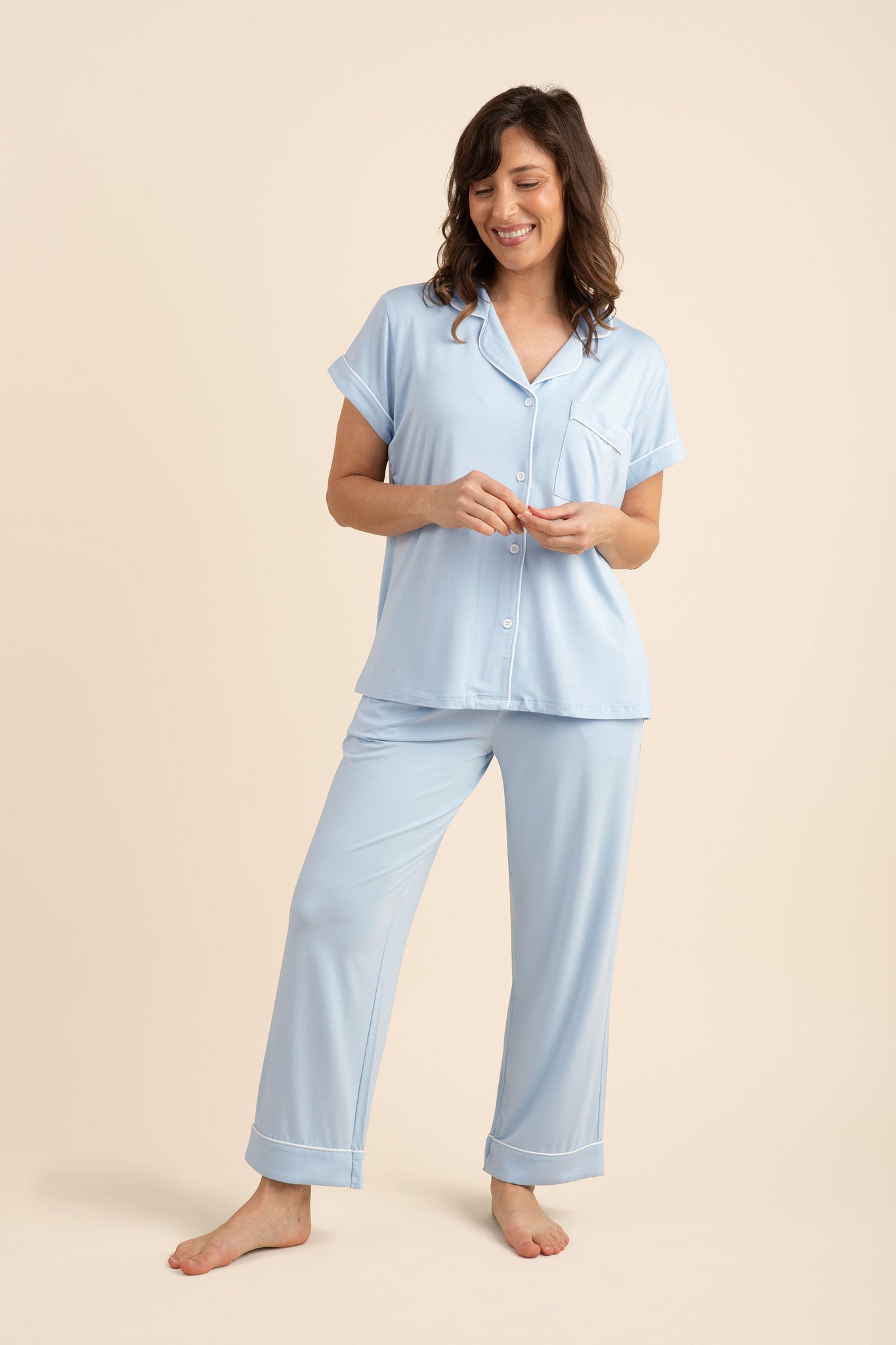 Smiling model wearing the Women's Short Sleeve Cropped Pajama Set in Breeze standing in front of a light beige background