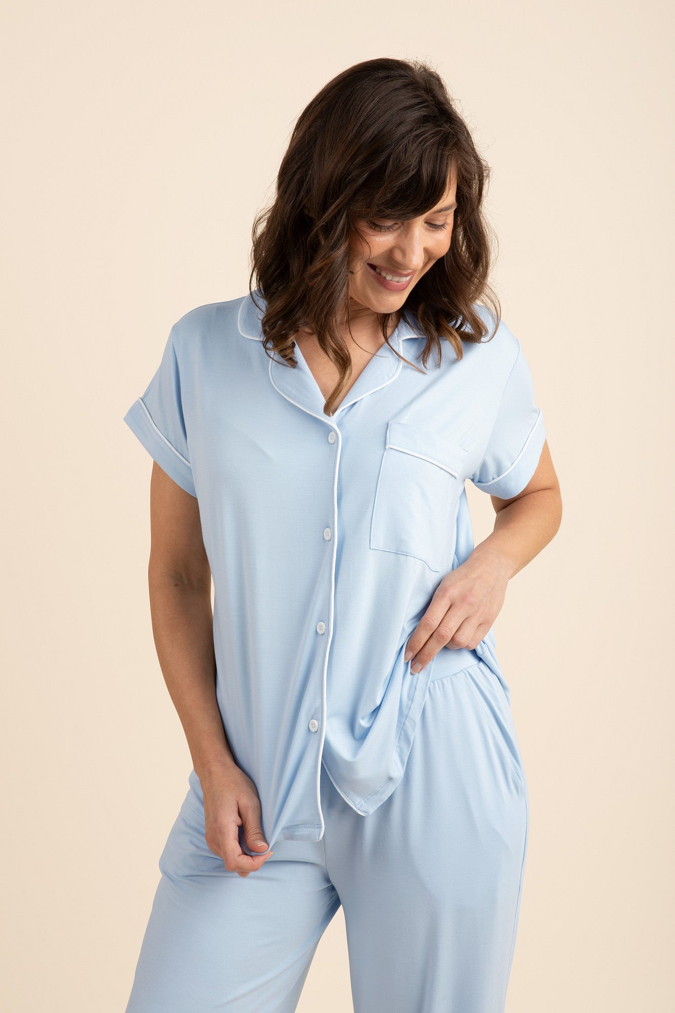 Female posing wearing the Women's Short Sleeve Cropped Pajama Set in Breeze standing in front of a light beige background