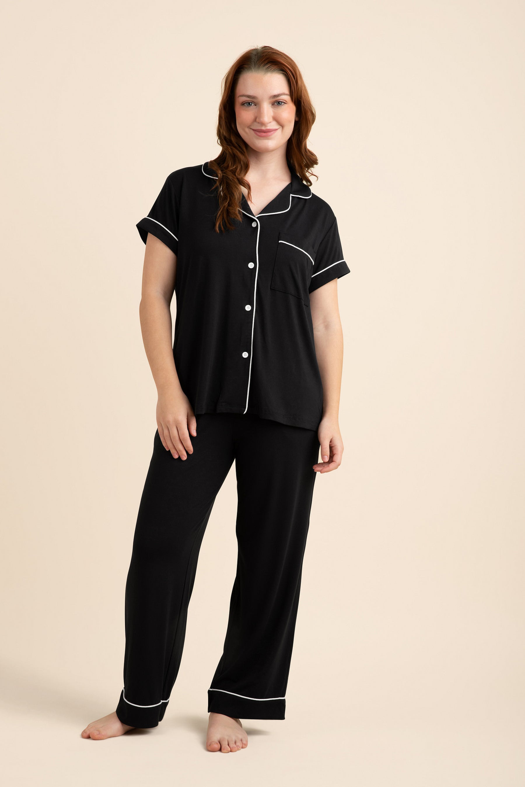 Female posing wearing the Women's Short Sleeve Cropped Pajama Set in Midnight standing in front of a light beige background