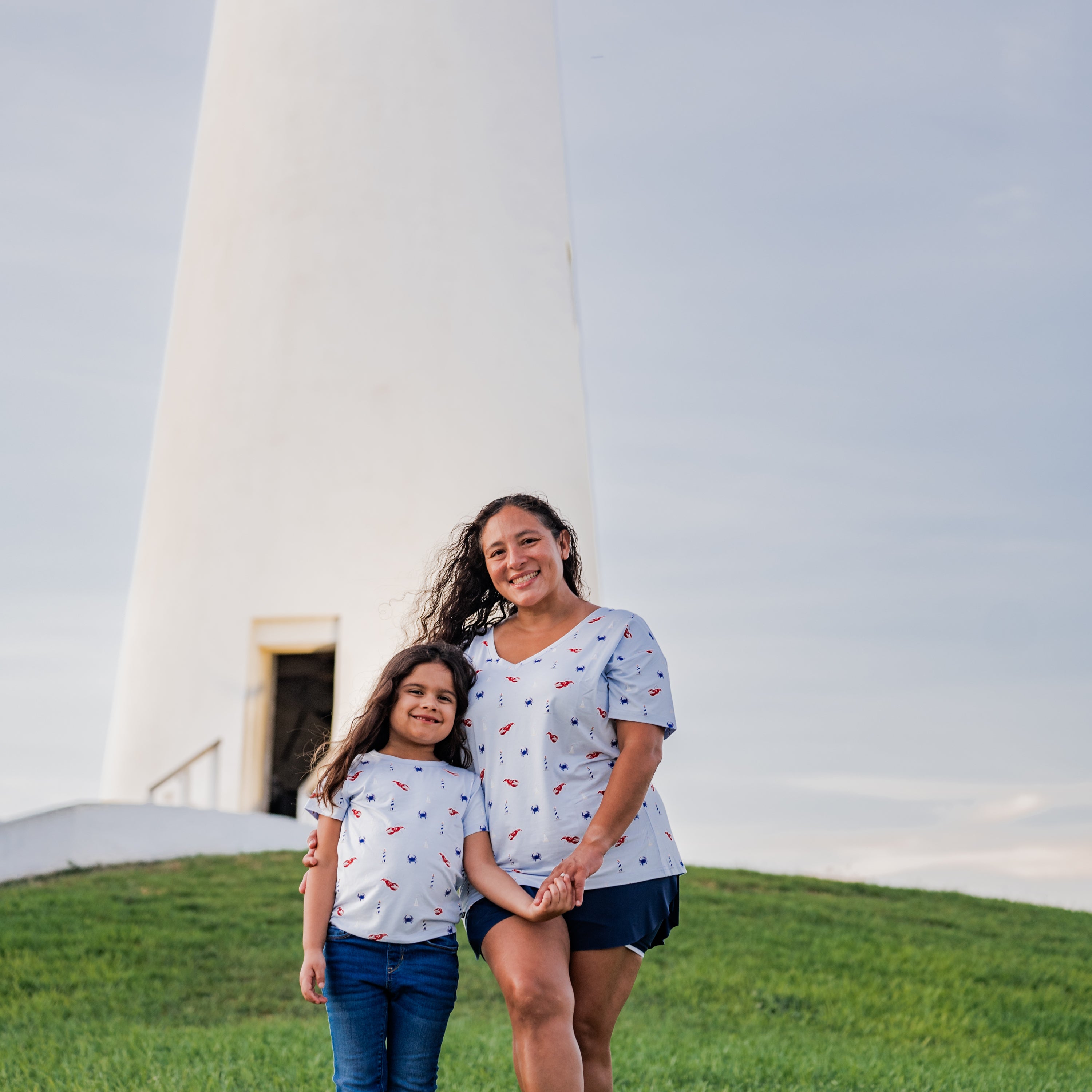 Mom and daughter matching in Harbor tees with a lighthouse background