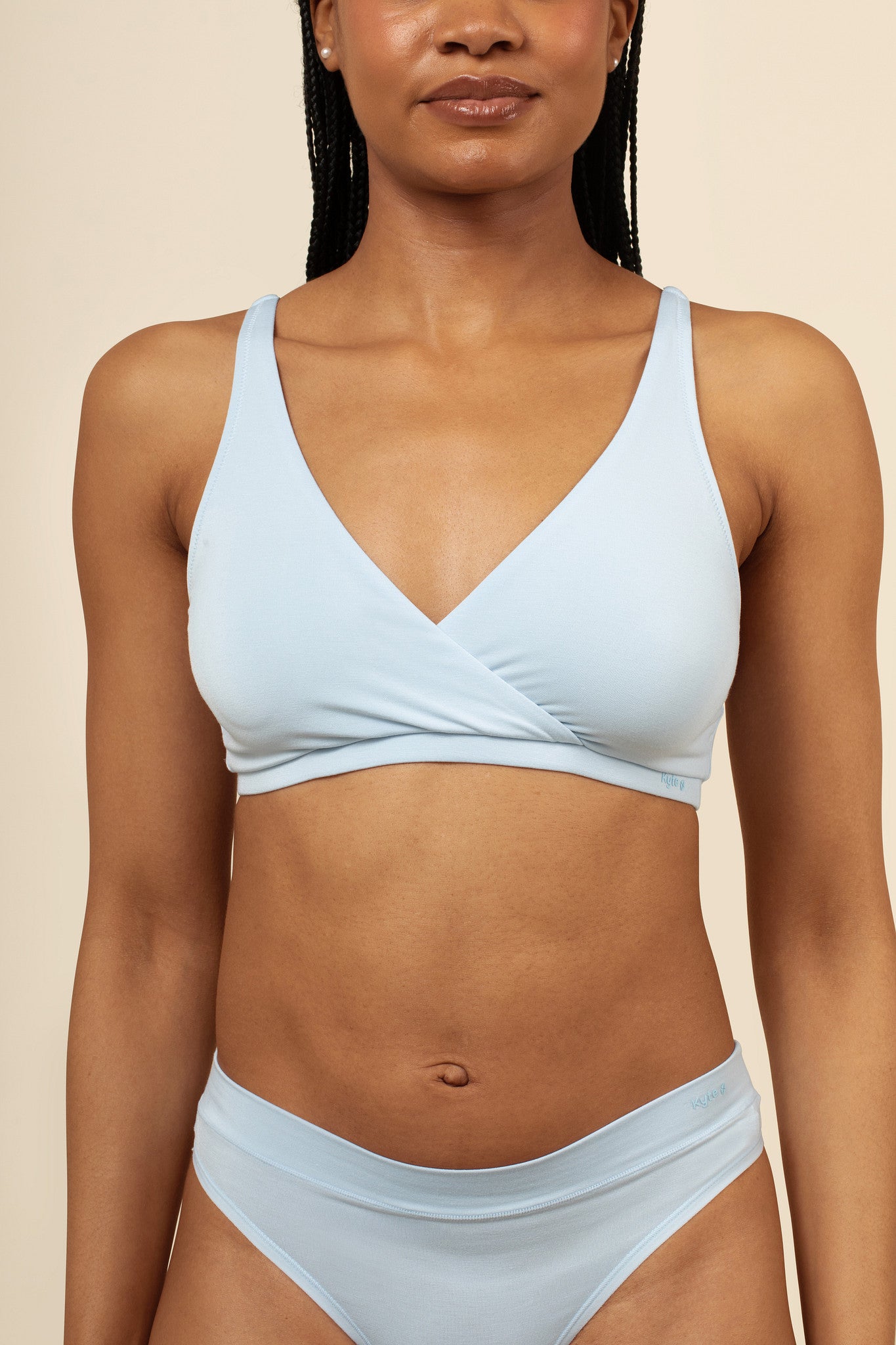 Woman wearing a light blue bra set against a beige background