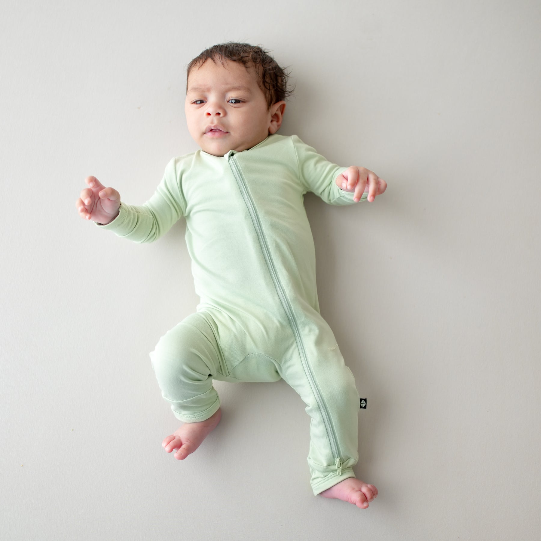 Baby wearing a light green zippered romper