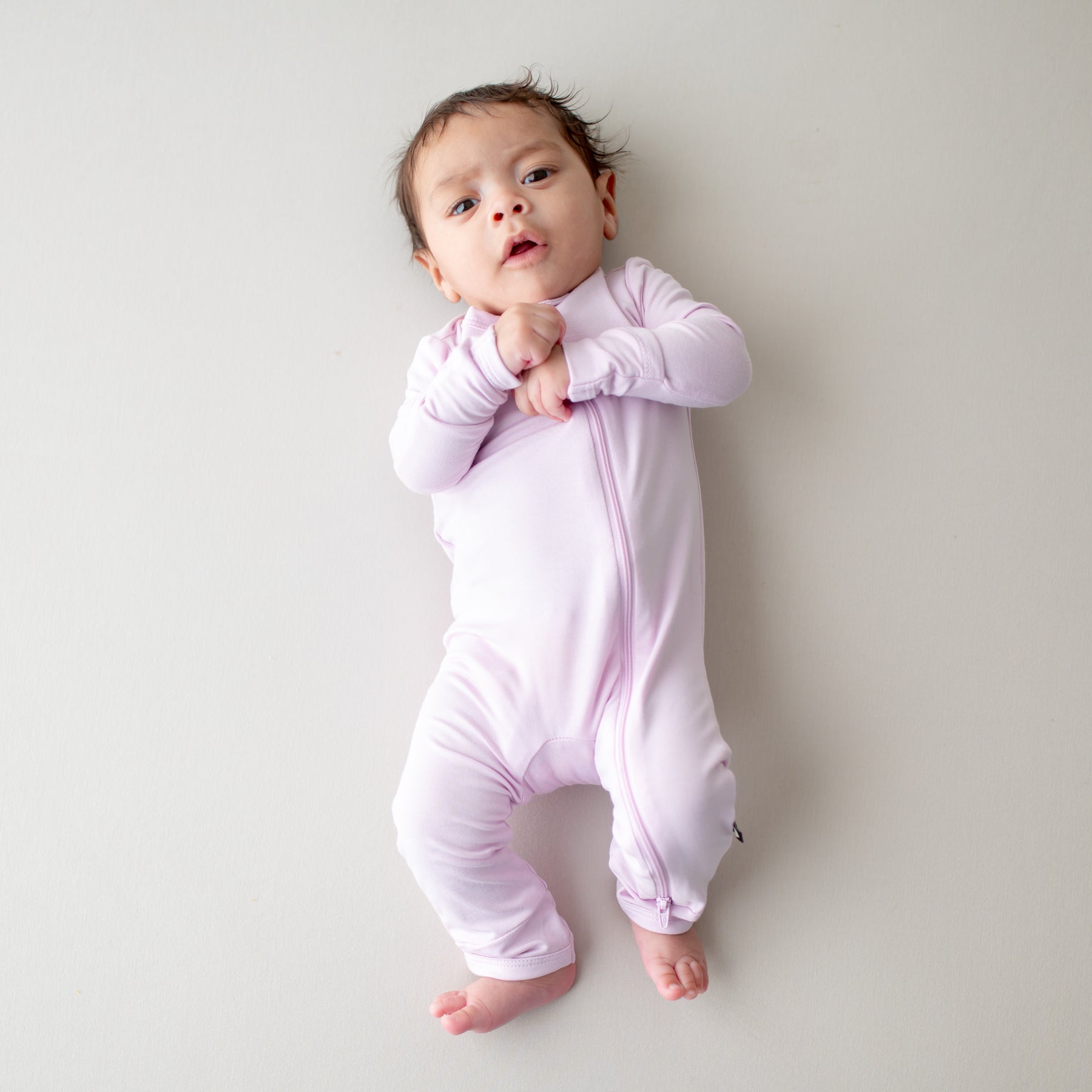 Baby wearing a zippered romper in a light purple color