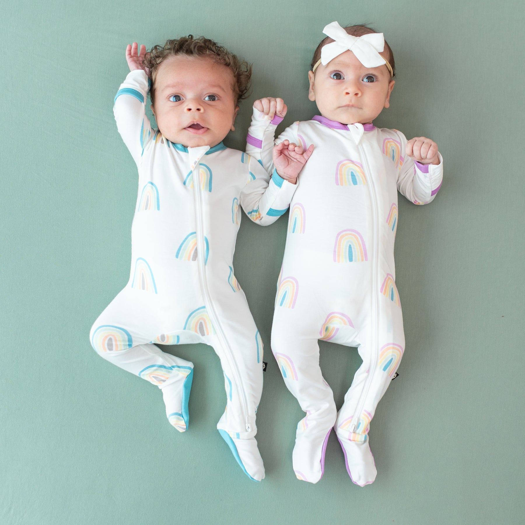 Two babies in Zippered Footies in Makai and Poi Rainbow