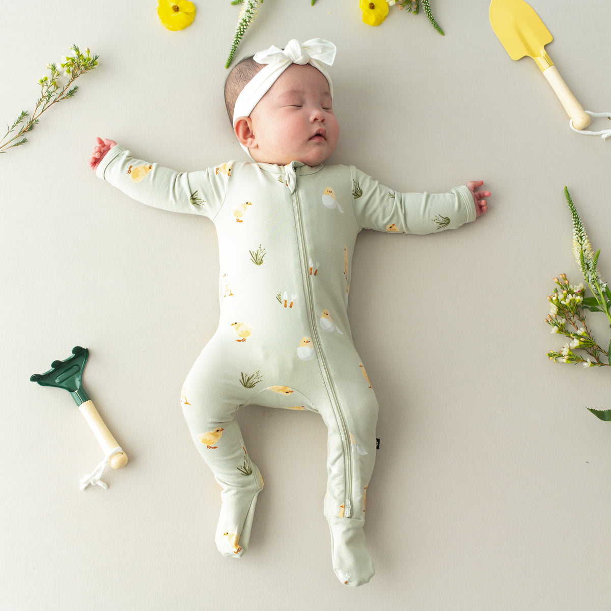 Baby sleeping wearing Zippered Footie in Aloe Chick