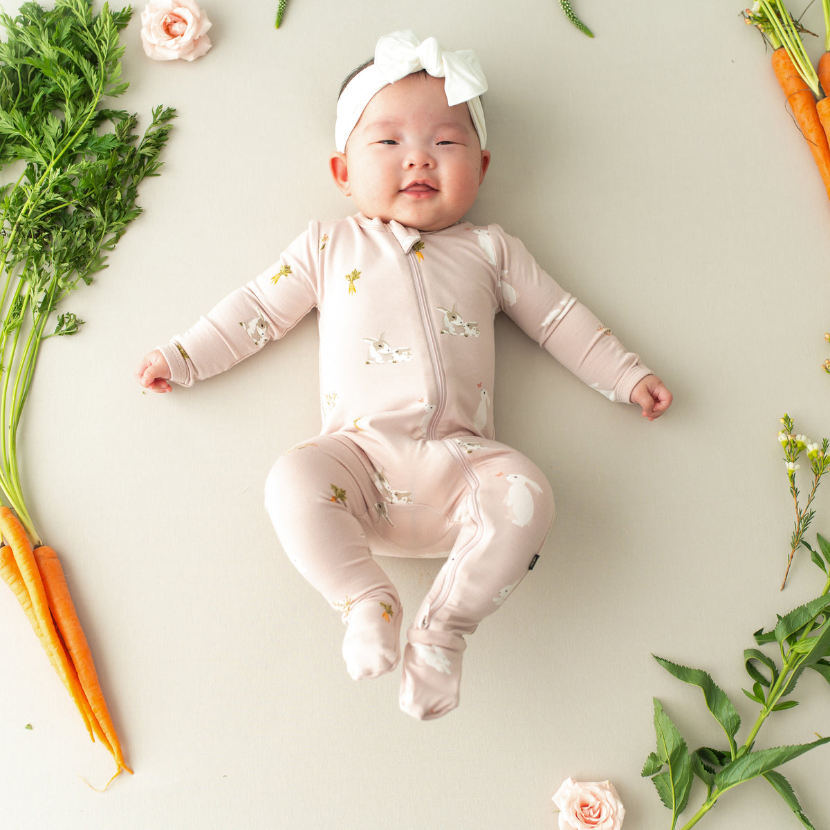 baby smiling wearing Zippered Footie in Blush Rabbit