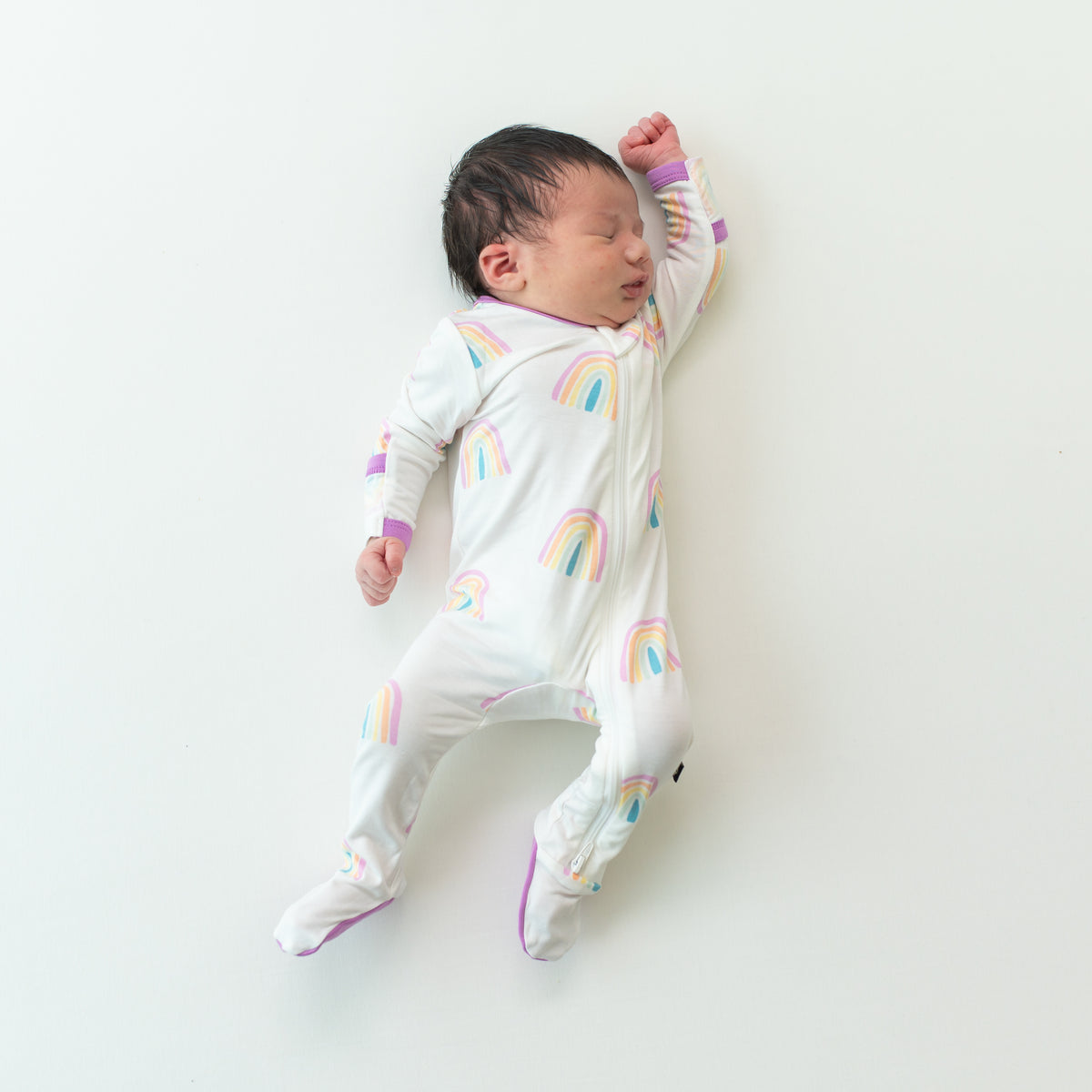 Baby asleep in Zippered Footie in Poi Rainbow