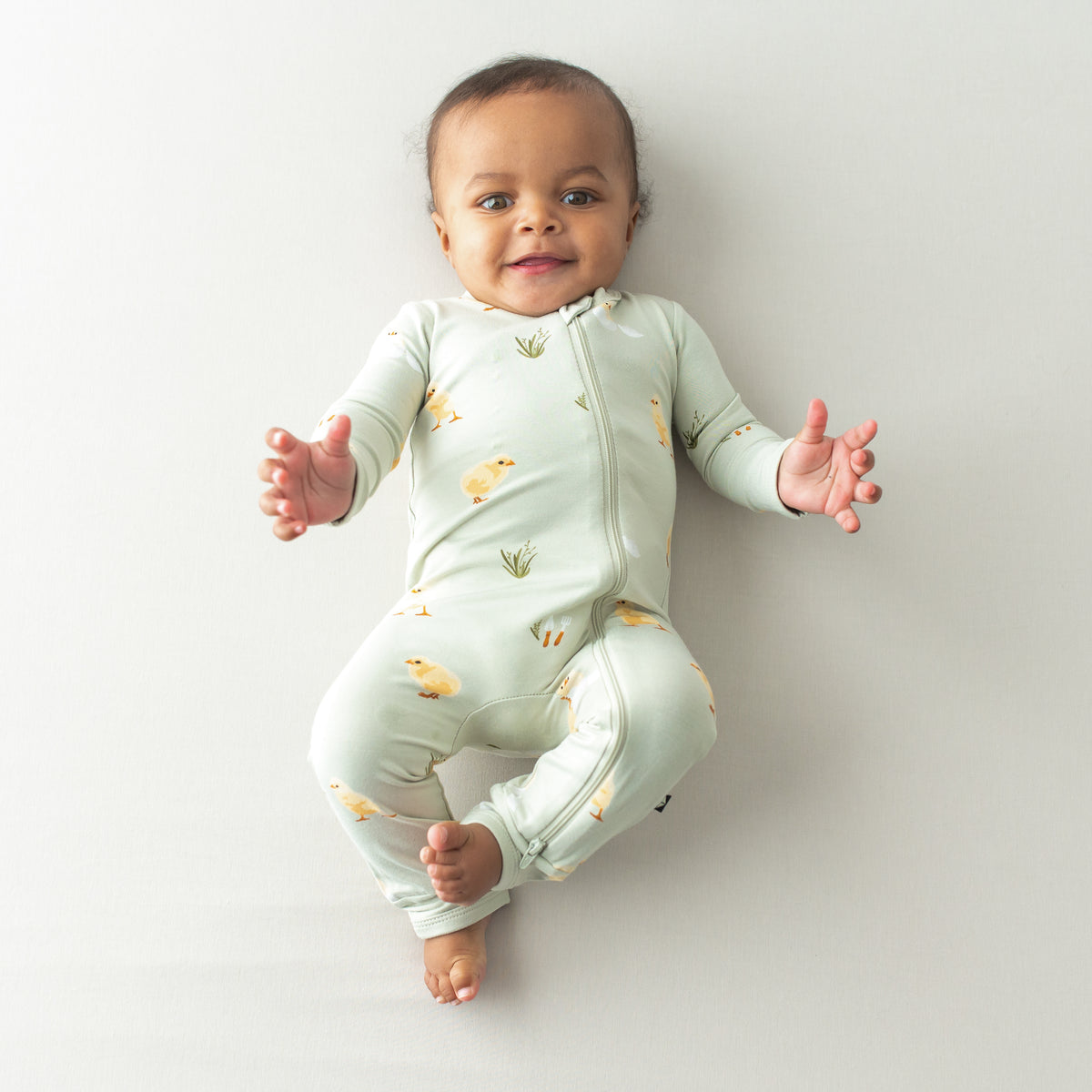 Baby wearing Zippered Romper in Aloe Chick