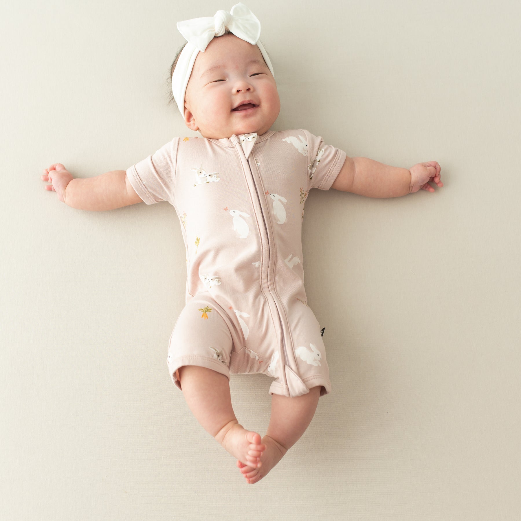 baby smiling wearing Zipper Shortall Romper in Blush Rabbit