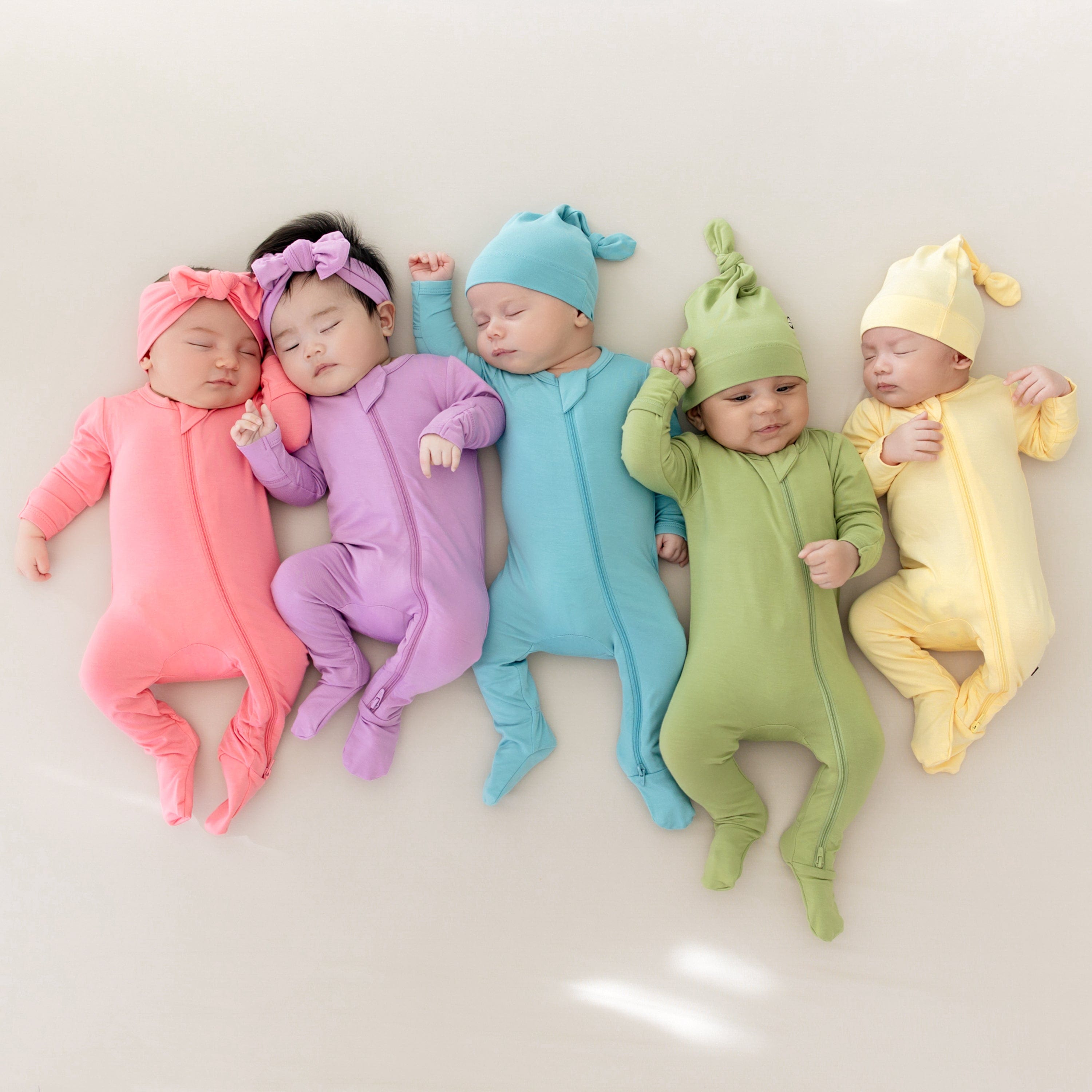 5 babies in kyte baby zippered footies in spring 2025 solids