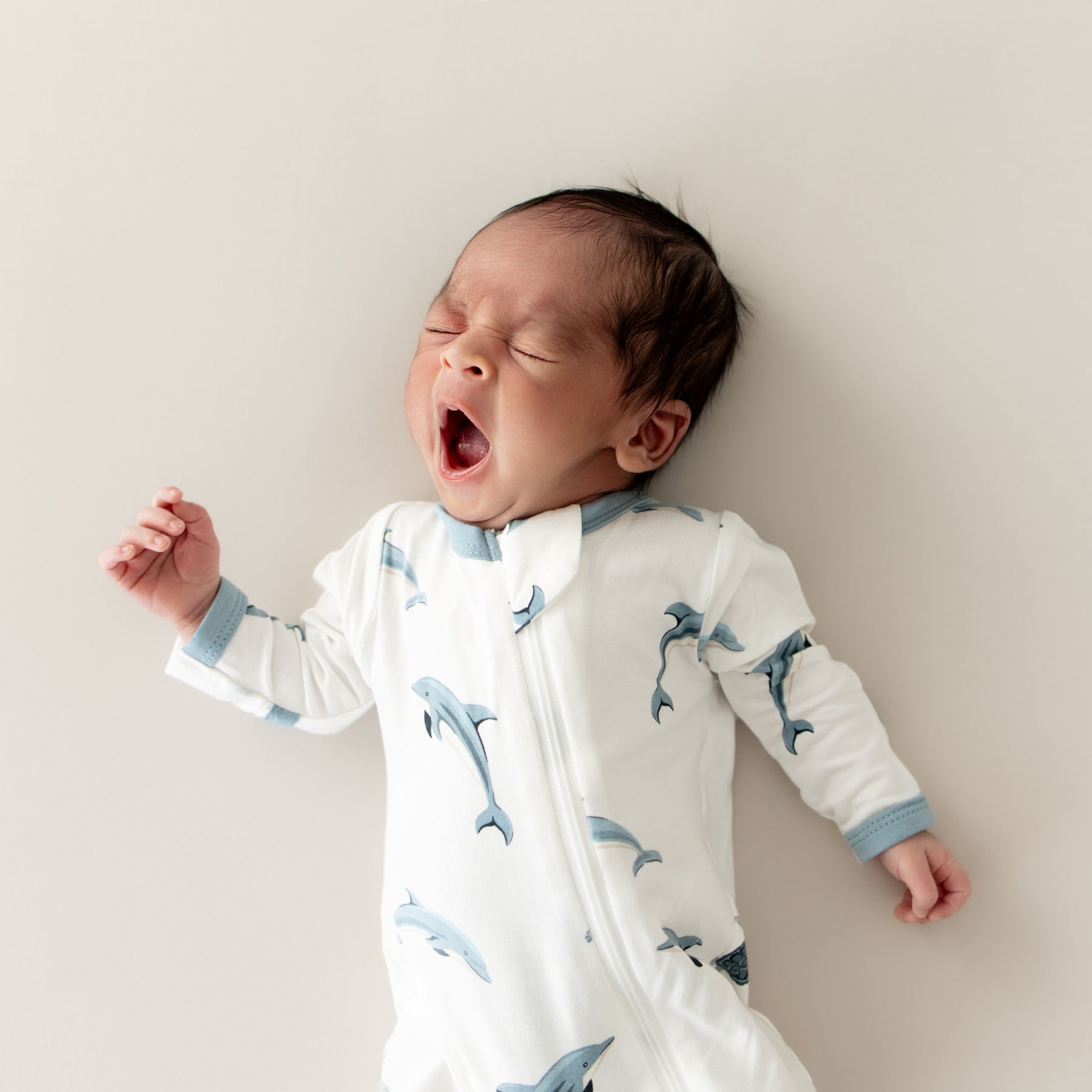 baby yawing and wearing Zippered Footie in Dolphin