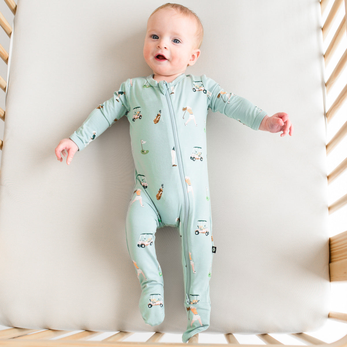 Baby modeling Zippered Footie in Golf in a crib