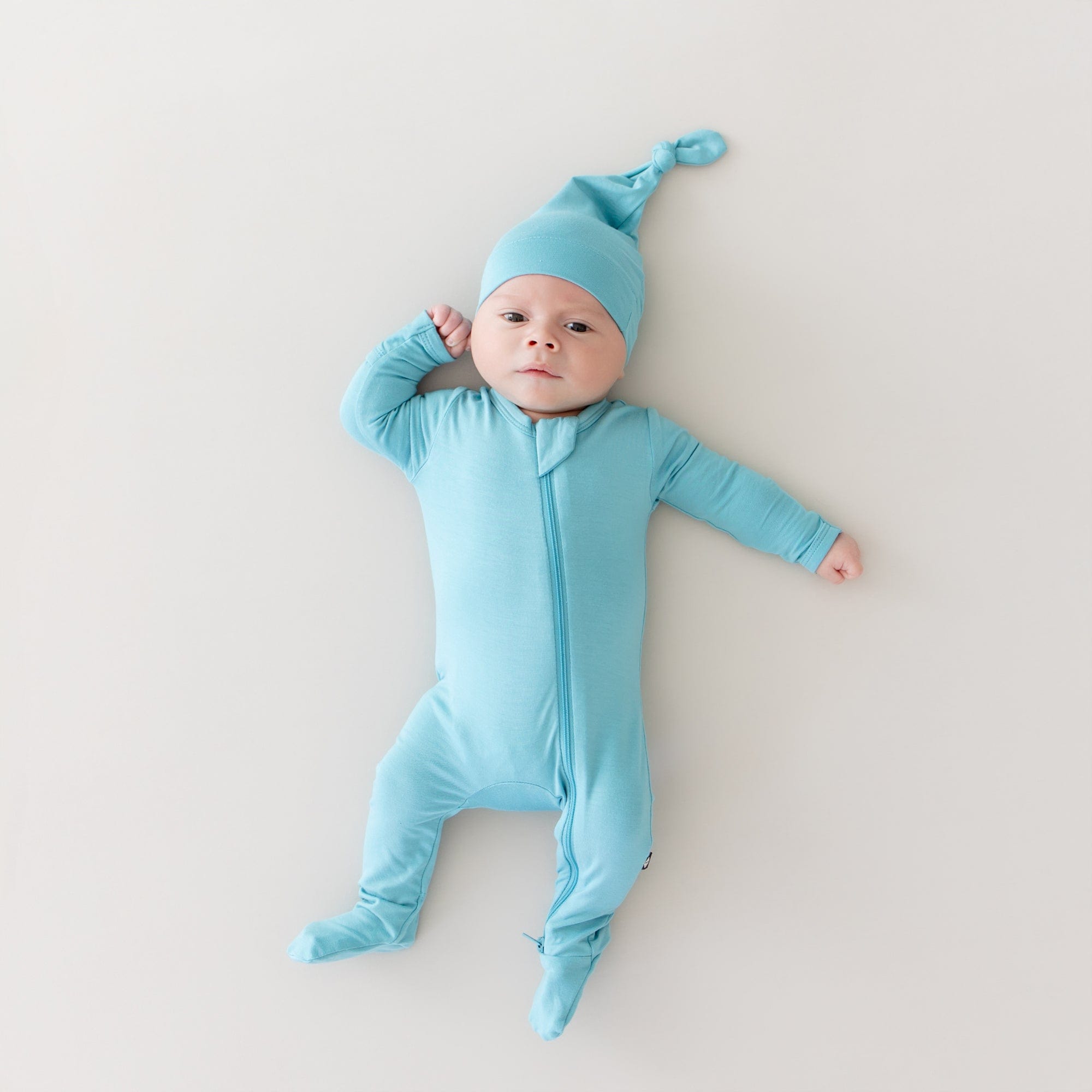 baby modeling kyte baby zippered footie and knotted cap in makai 