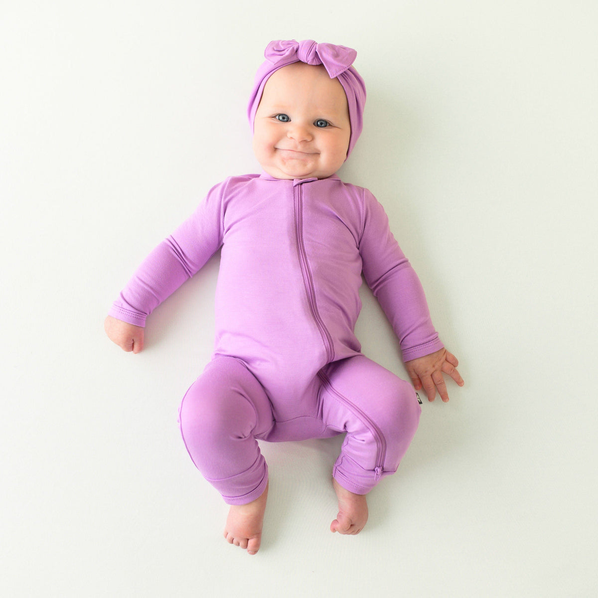 baby wearing zippered romper and bow in poi