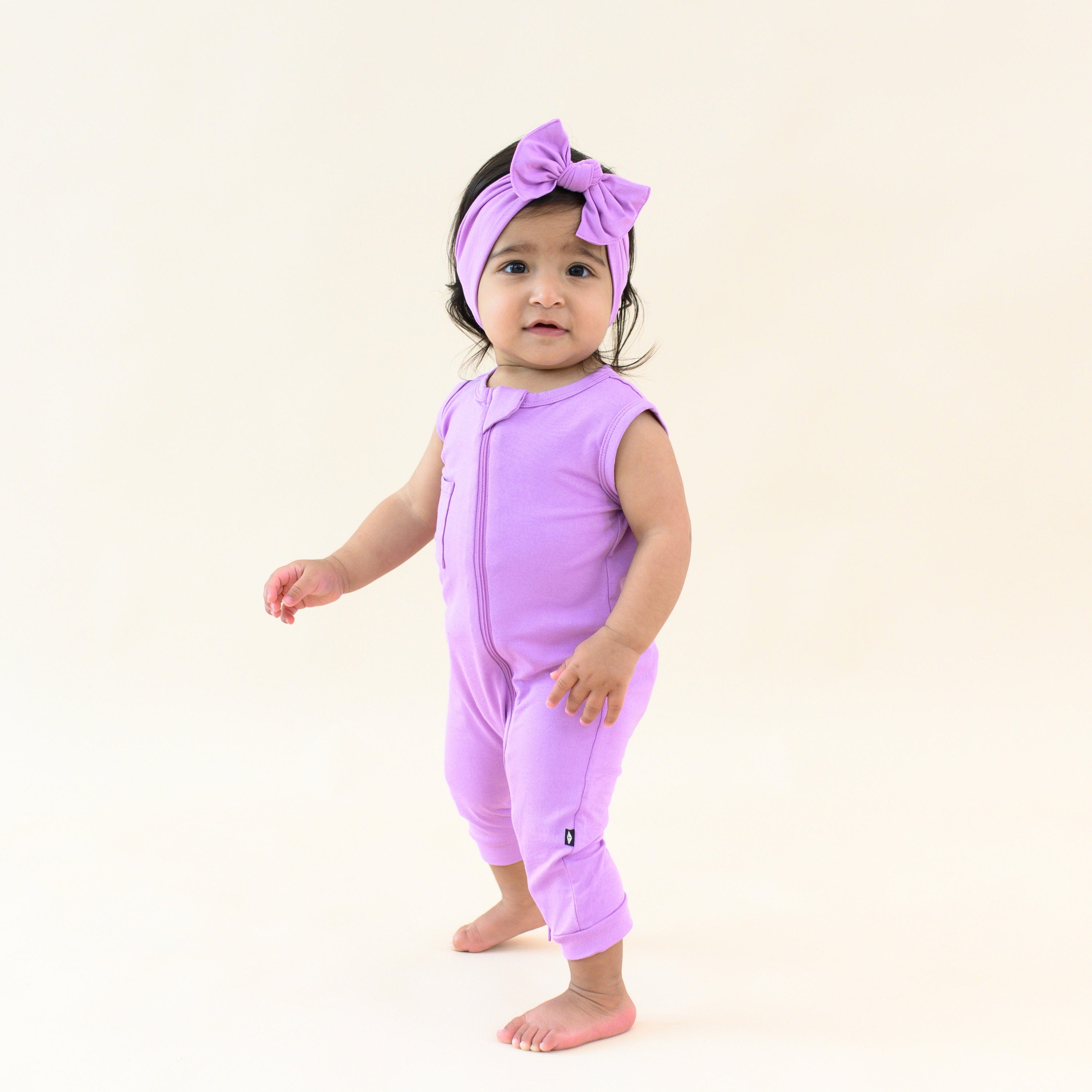 baby wearing sleeveless zippered romper and bow in poi