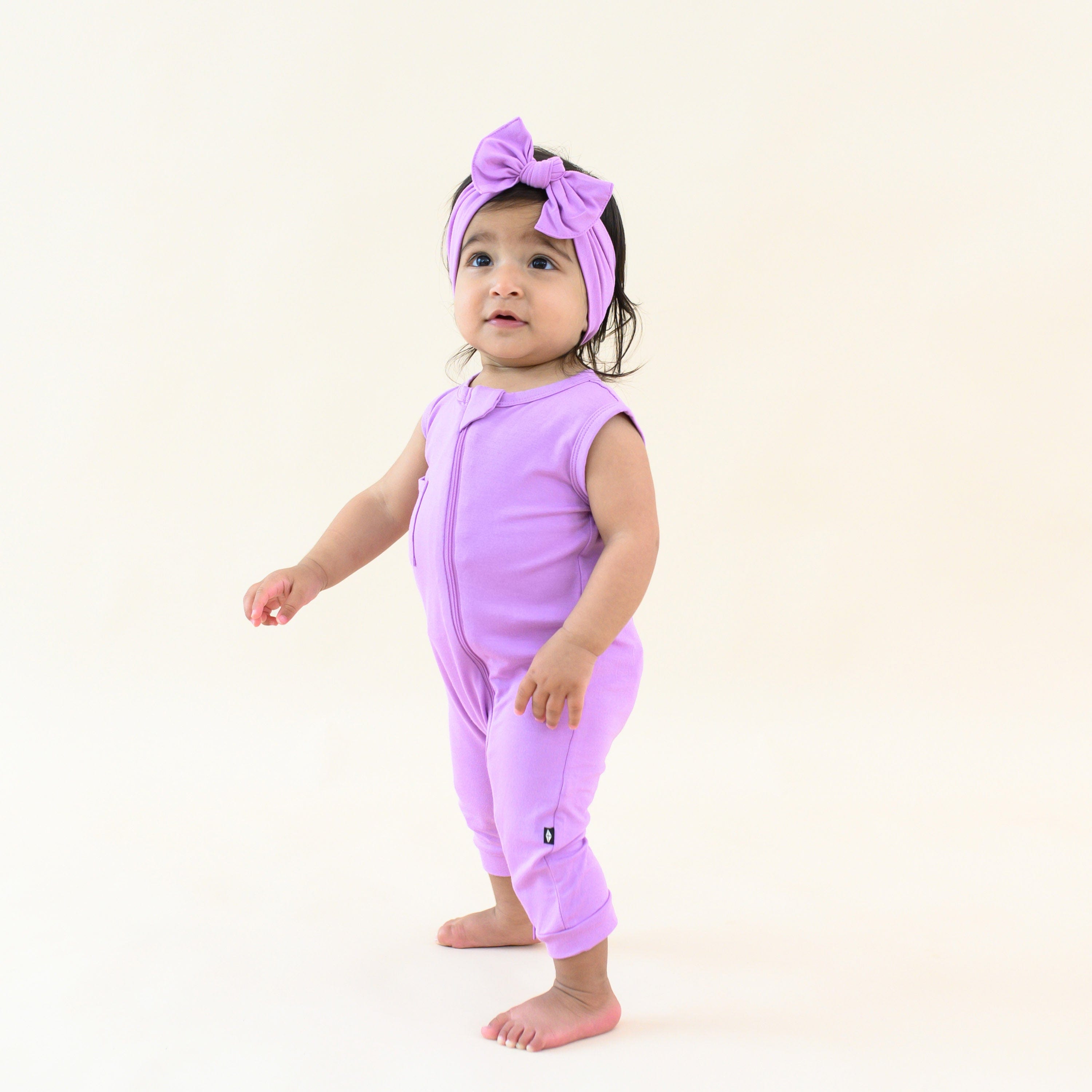 toddler wearing zippered sleeveless romper and bow in poi