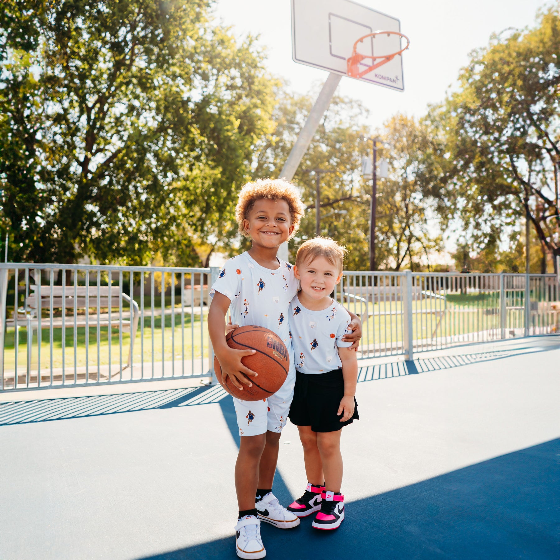 Young boy and girl standing beside each other on a basketball court matching in the Toddler Basic Tee in Basketball