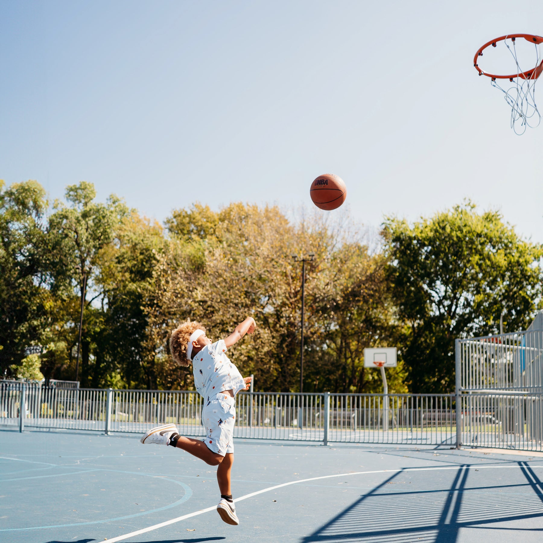 Young boy shooting a basketball wearing the Drawstring Short in Basketball and matching basic tee