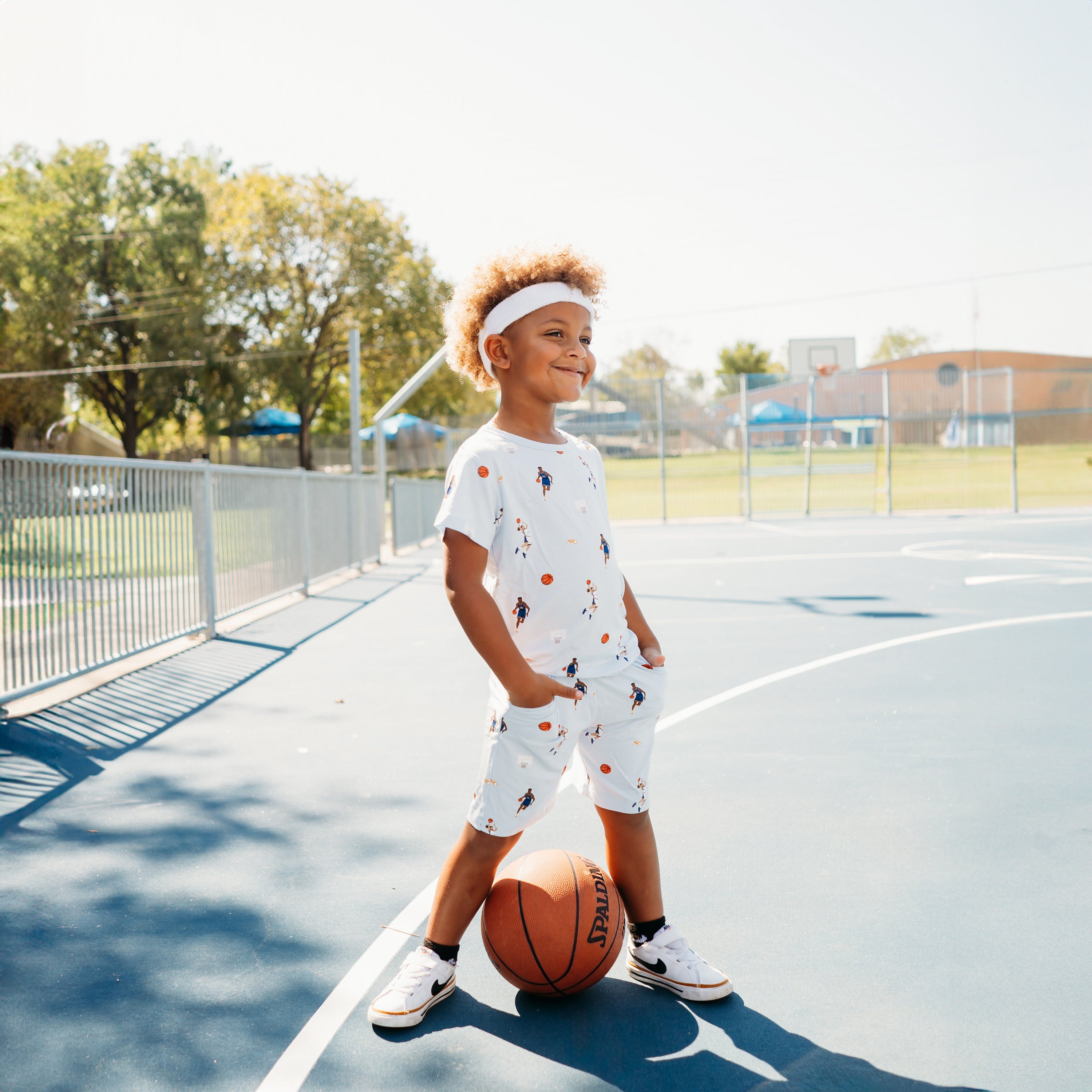 Young boy standing on a basketball court with his hands in the pockets of the Drawstring Short in Basketball wearing a matching basic tee