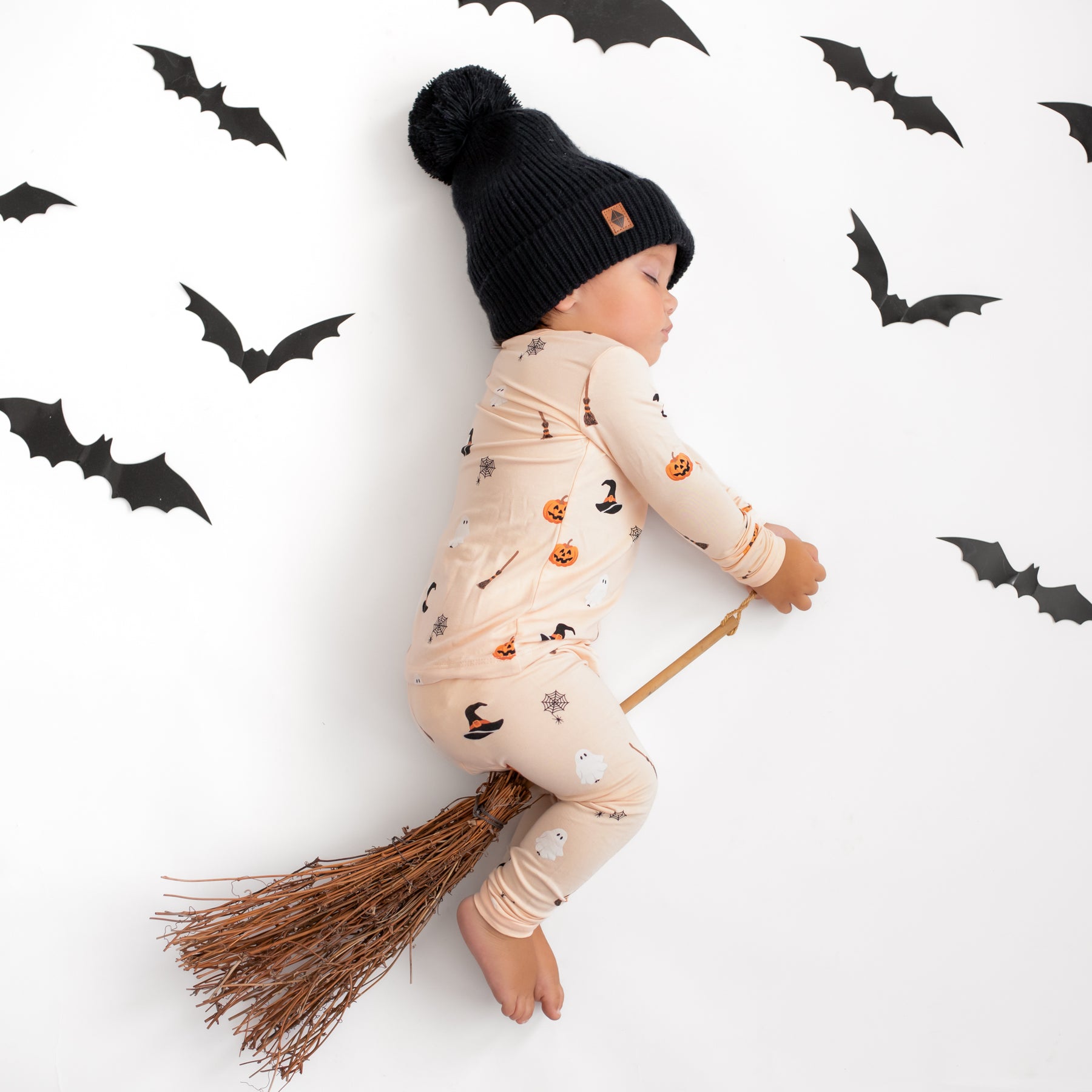 Baby wearing Long Sleeve Halloween Pajamas in Bewitched and Chunky Knit Pom Beanie in Midnight 