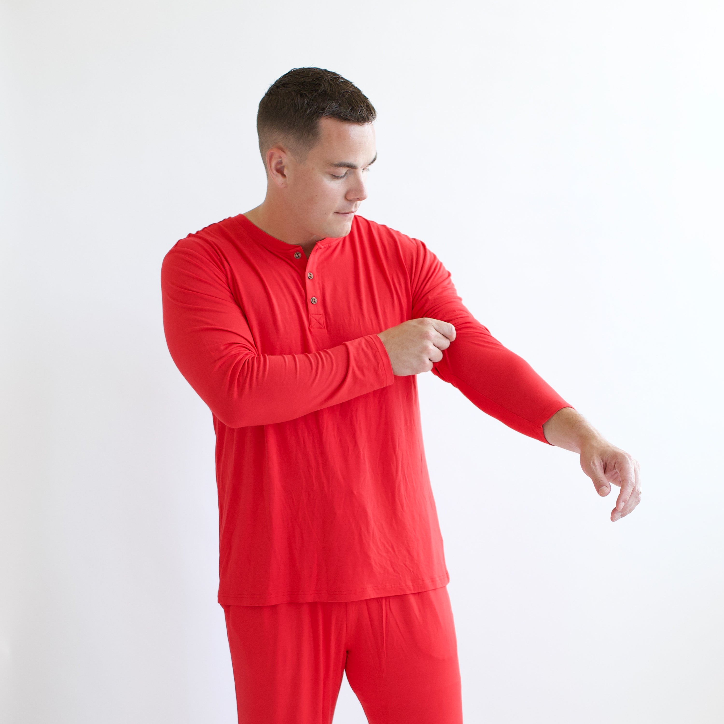 Male model pulling the sleeve up on the Men's Long Sleeve Henley Top in Cardinal