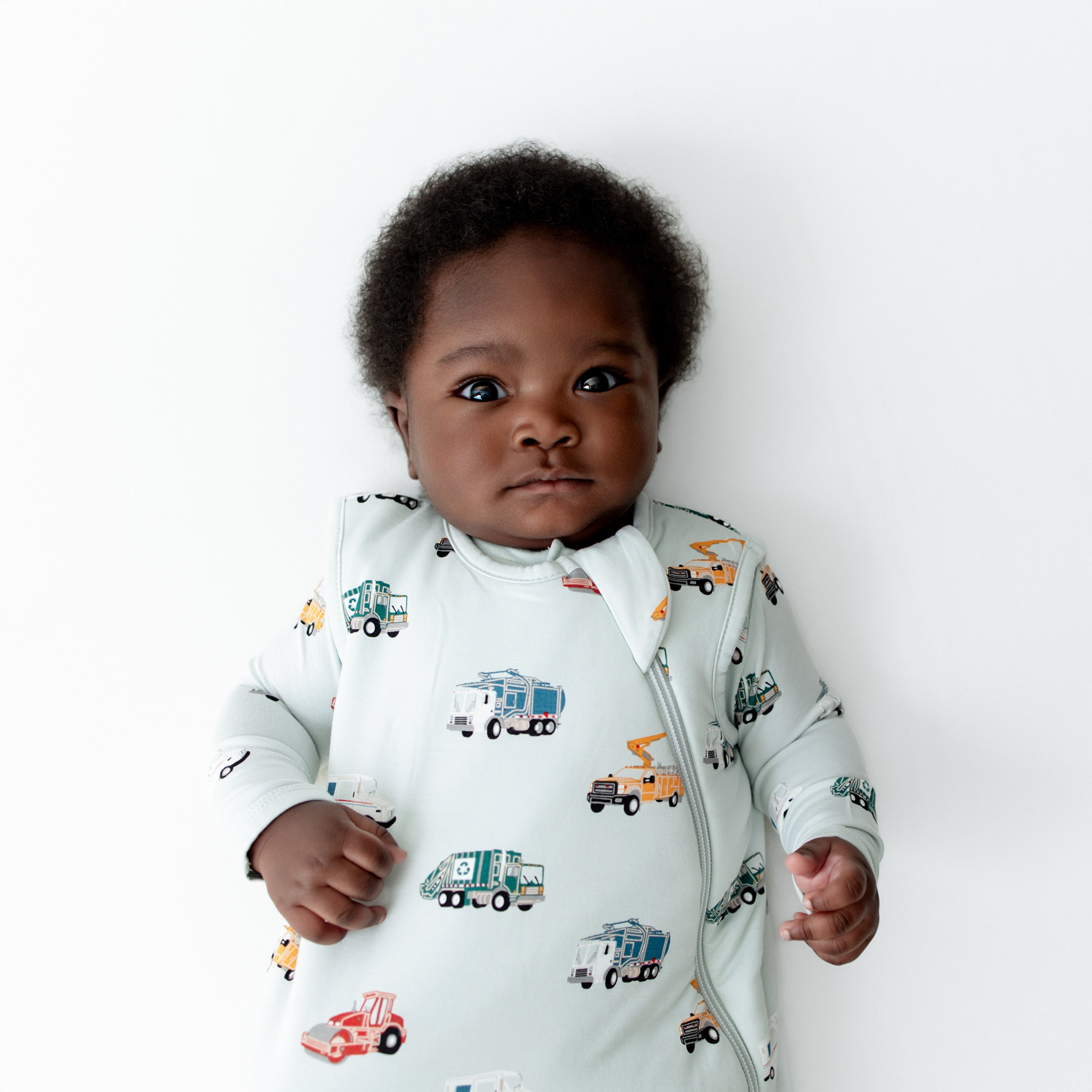 Close up of infant wearing the Sleep Bag in City Vehicles 1.0 with a matching romper on underneath