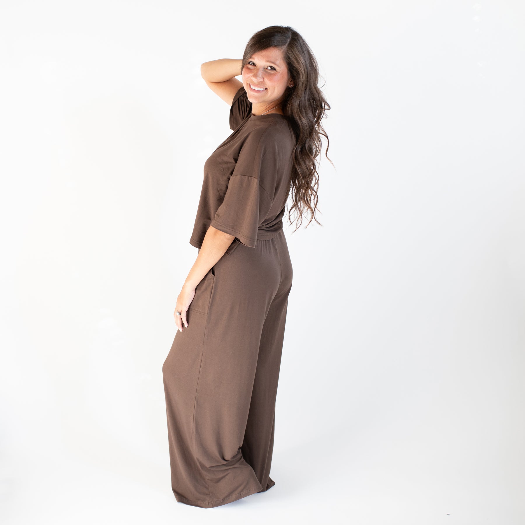 Woman wearing a brown jumpsuit on a white background