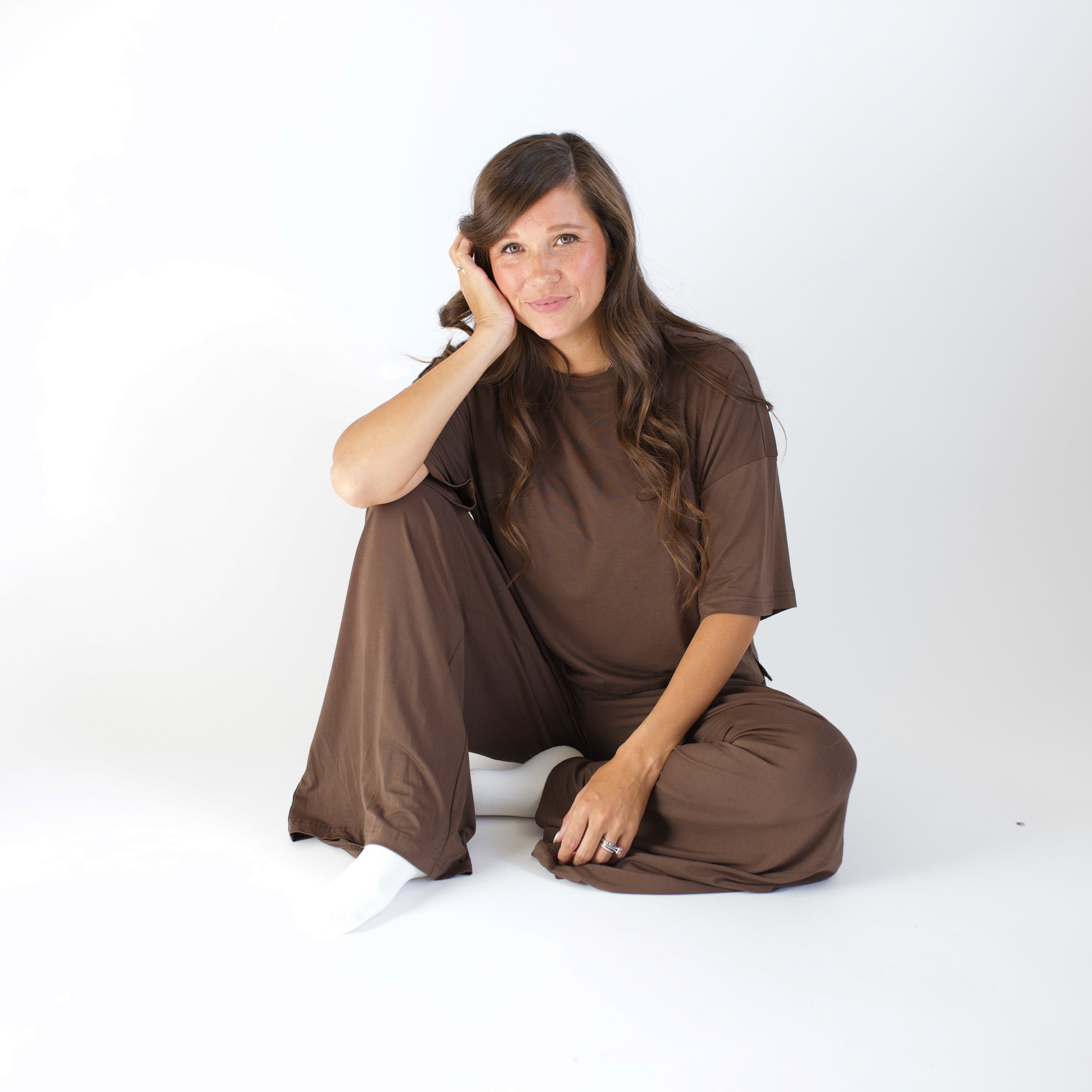 Woman wearing a brown outfit sitting on a white background