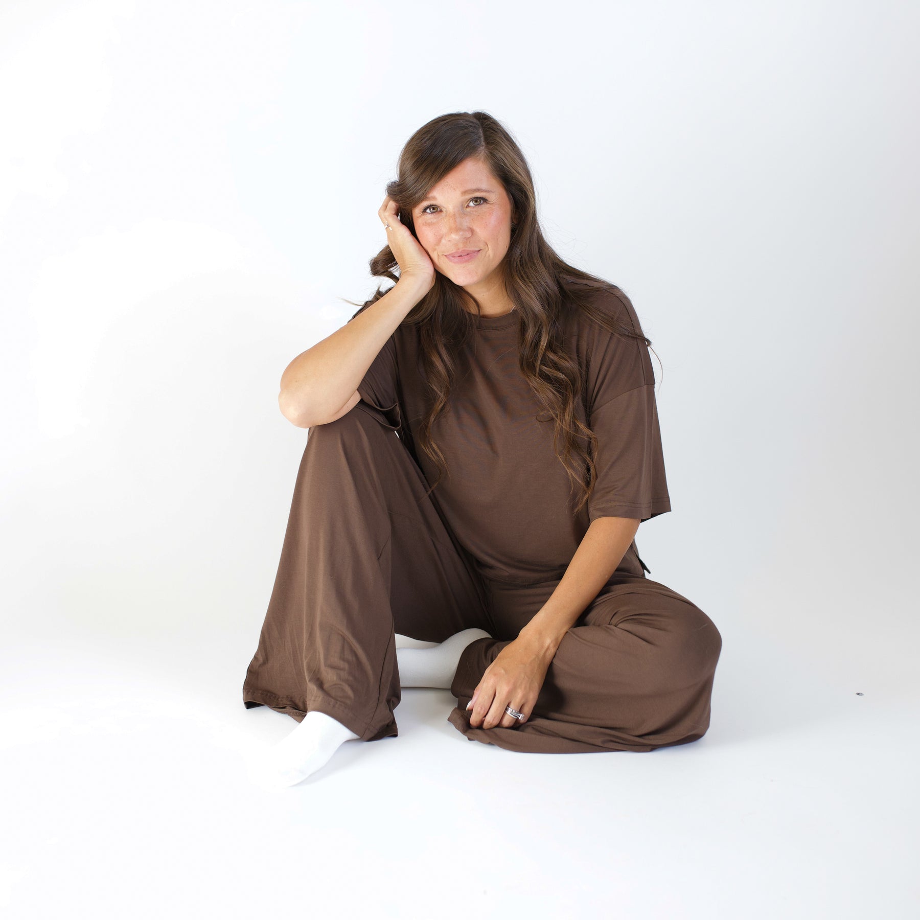 Woman wearing a brown outfit sitting on a white background
