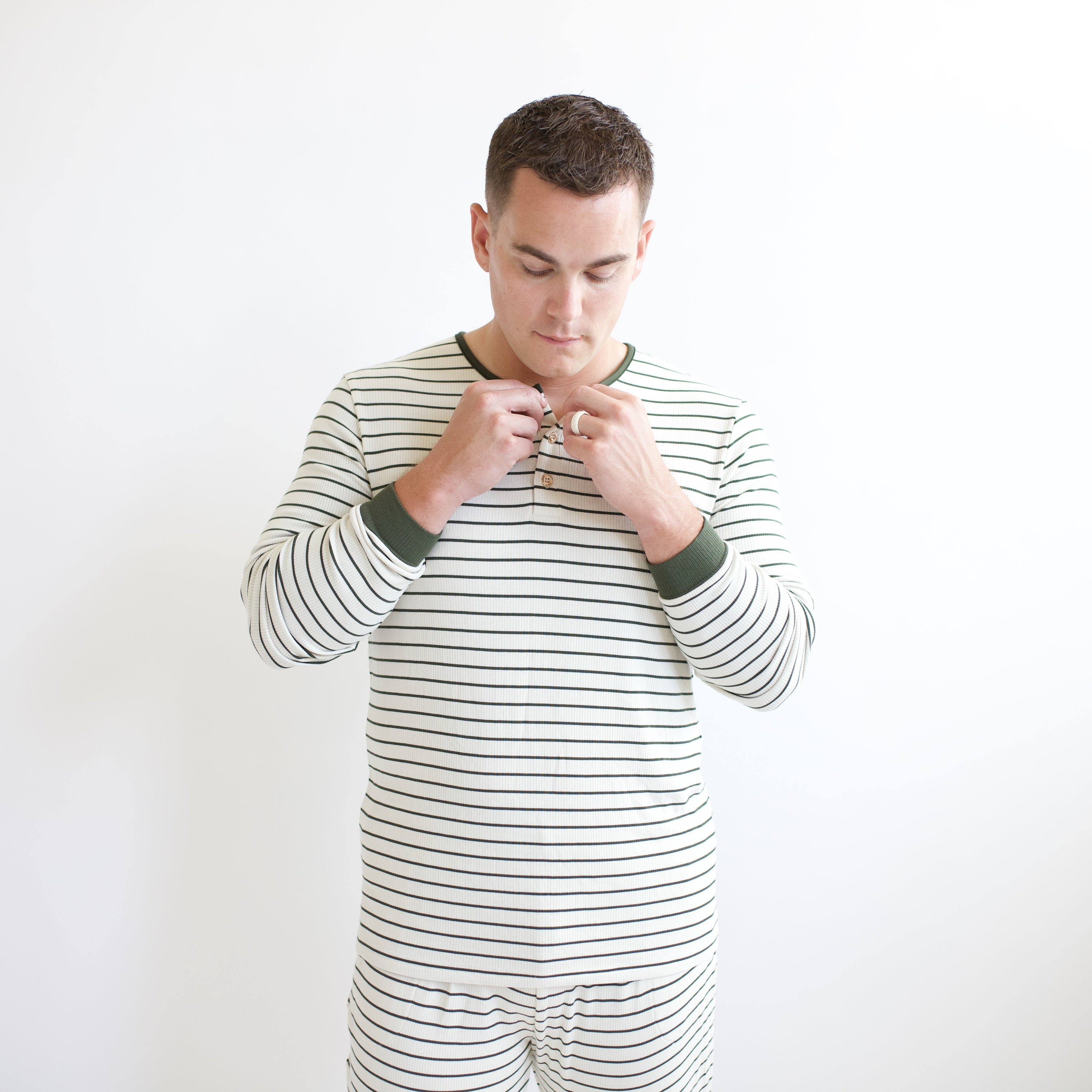 Male model buttoning up the buttons on the top of the Men's Ribbed Henley Set in Fir Stripe