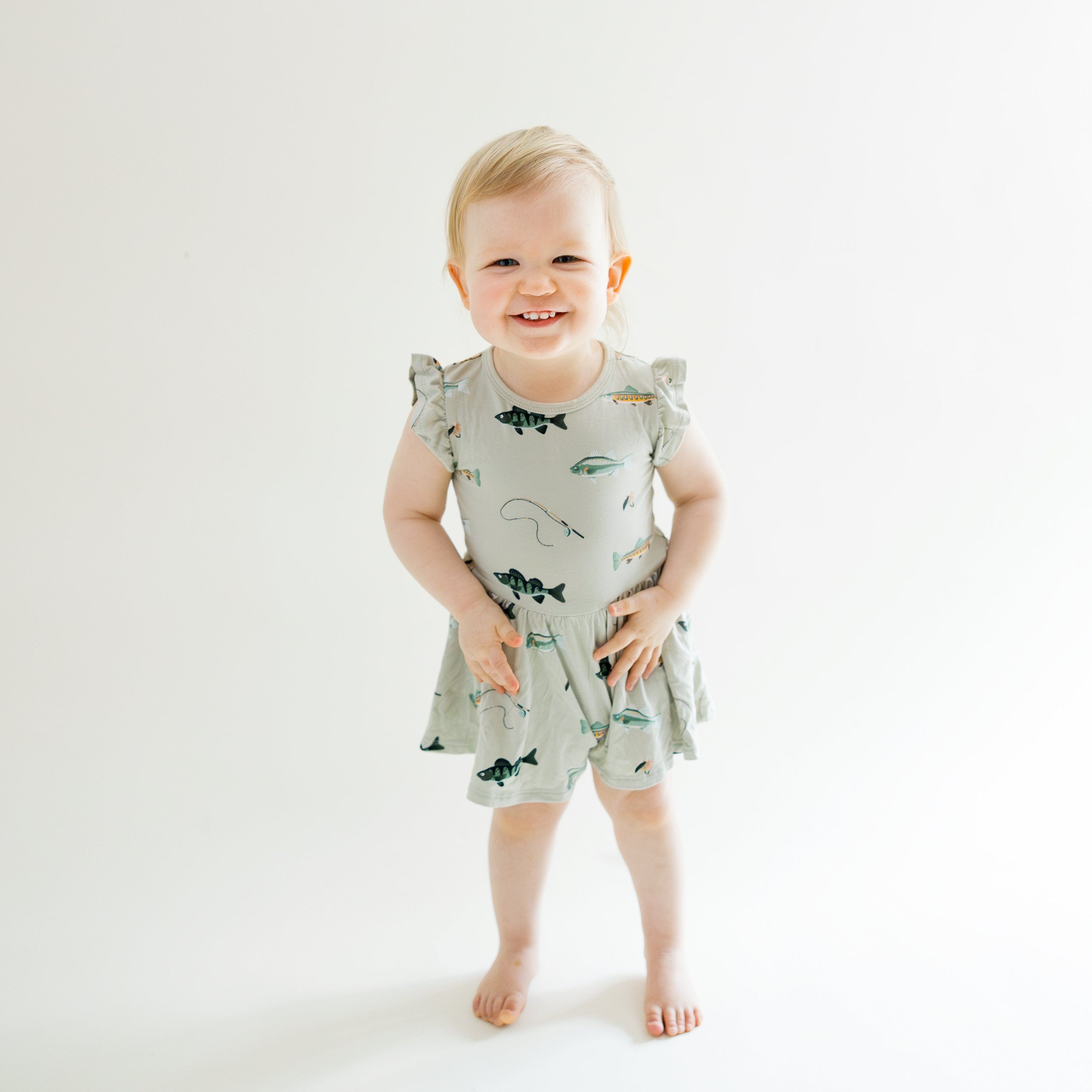 Toddler standing smiling wearing Twirl Bodysuit Dress in Fishing