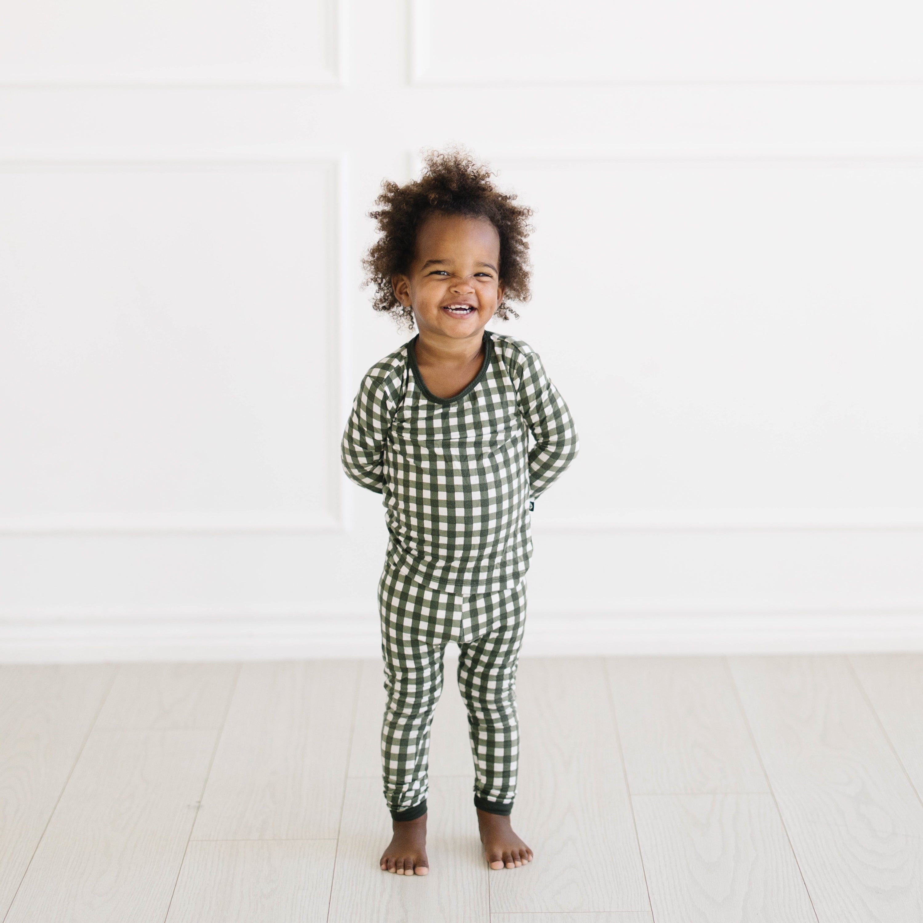 Smiling toddler wearing the Long Sleeve Pajamas in Gingham Fir