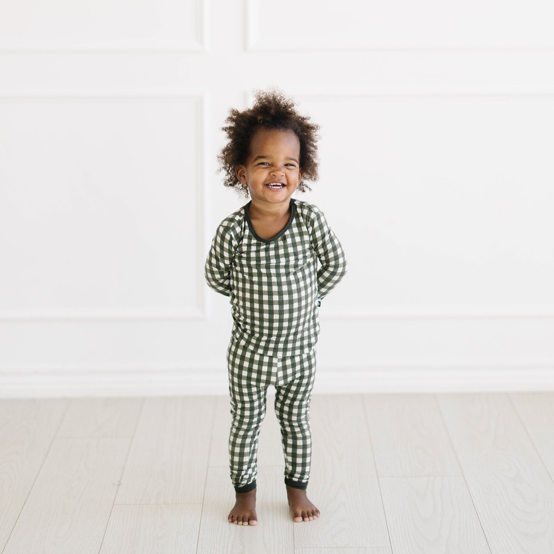 Smiling toddler wearing the Long Sleeve Pajamas in Gingham Fir