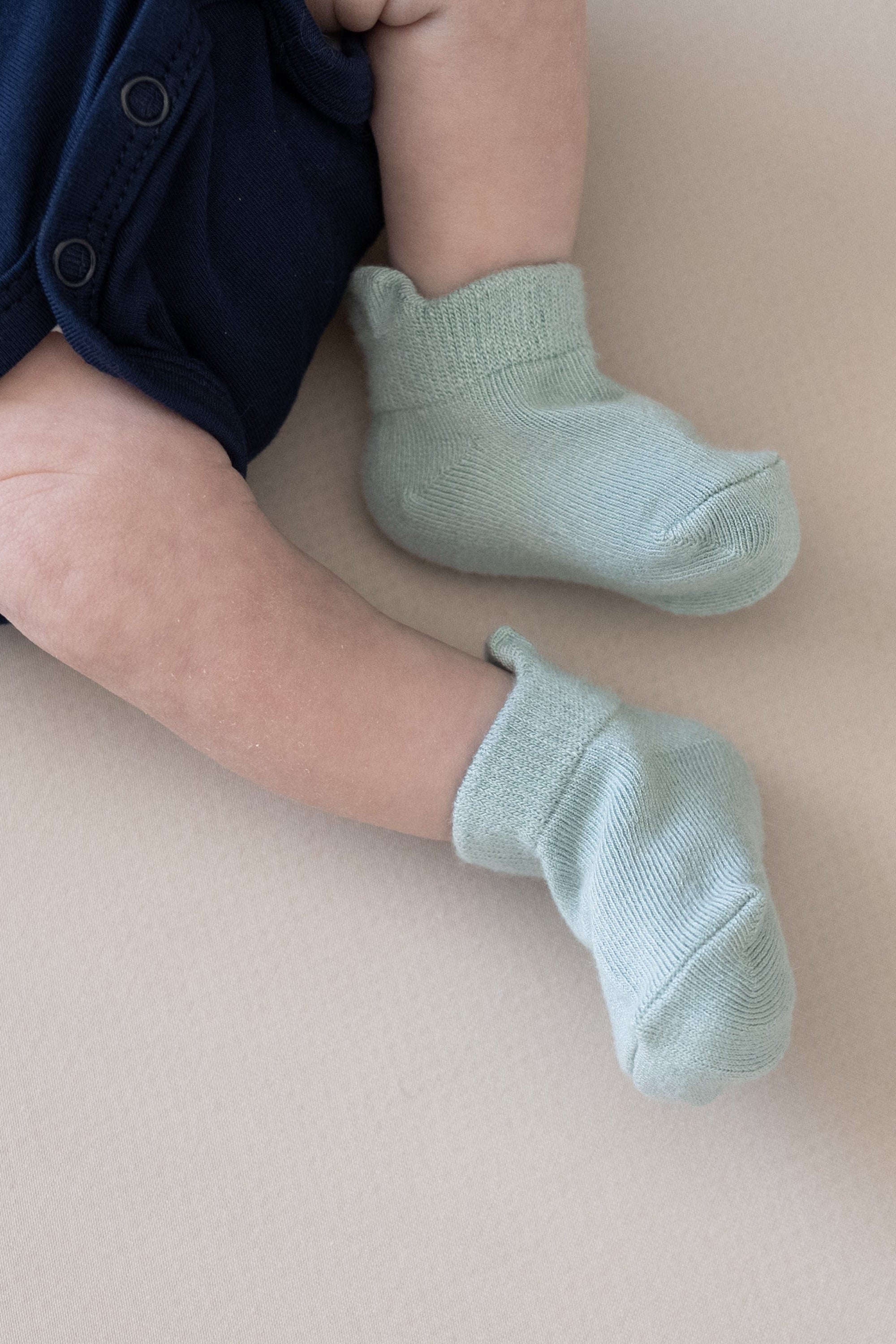 Newborn wearing Kyte Baby Ankle Socks in Neutral Blue Gray