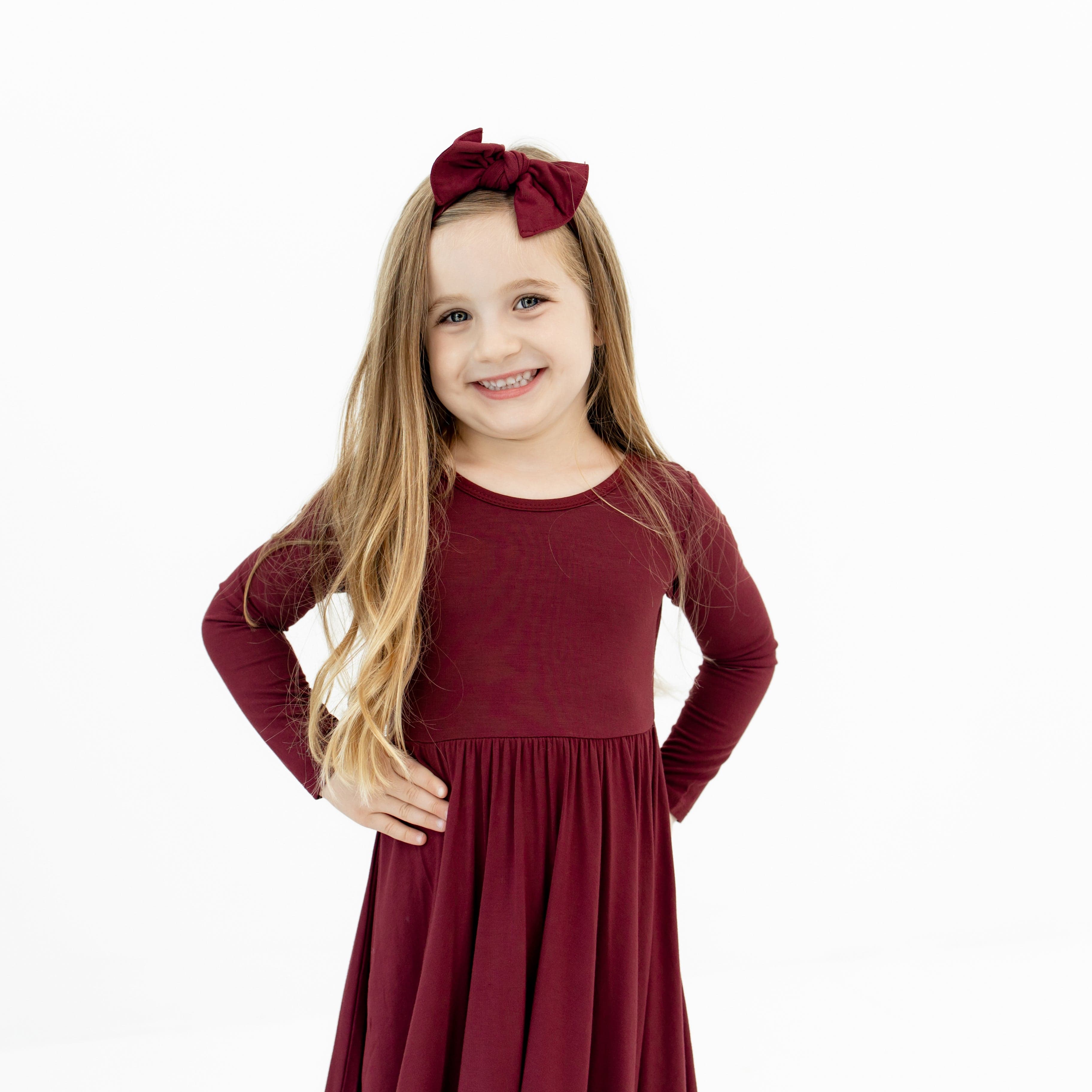 Girl wearing Knotted Bow Headband in Burgundy paired with matching twirl dress