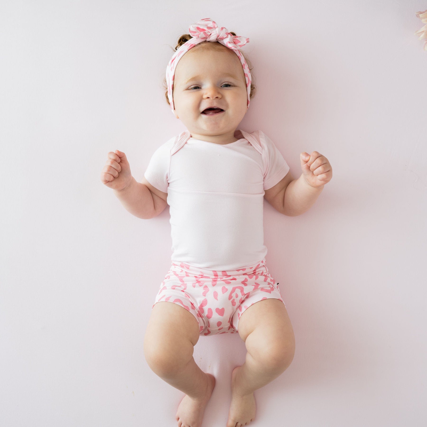 Infant wearing Kyte Baby Bow headband in Sakura Leopard