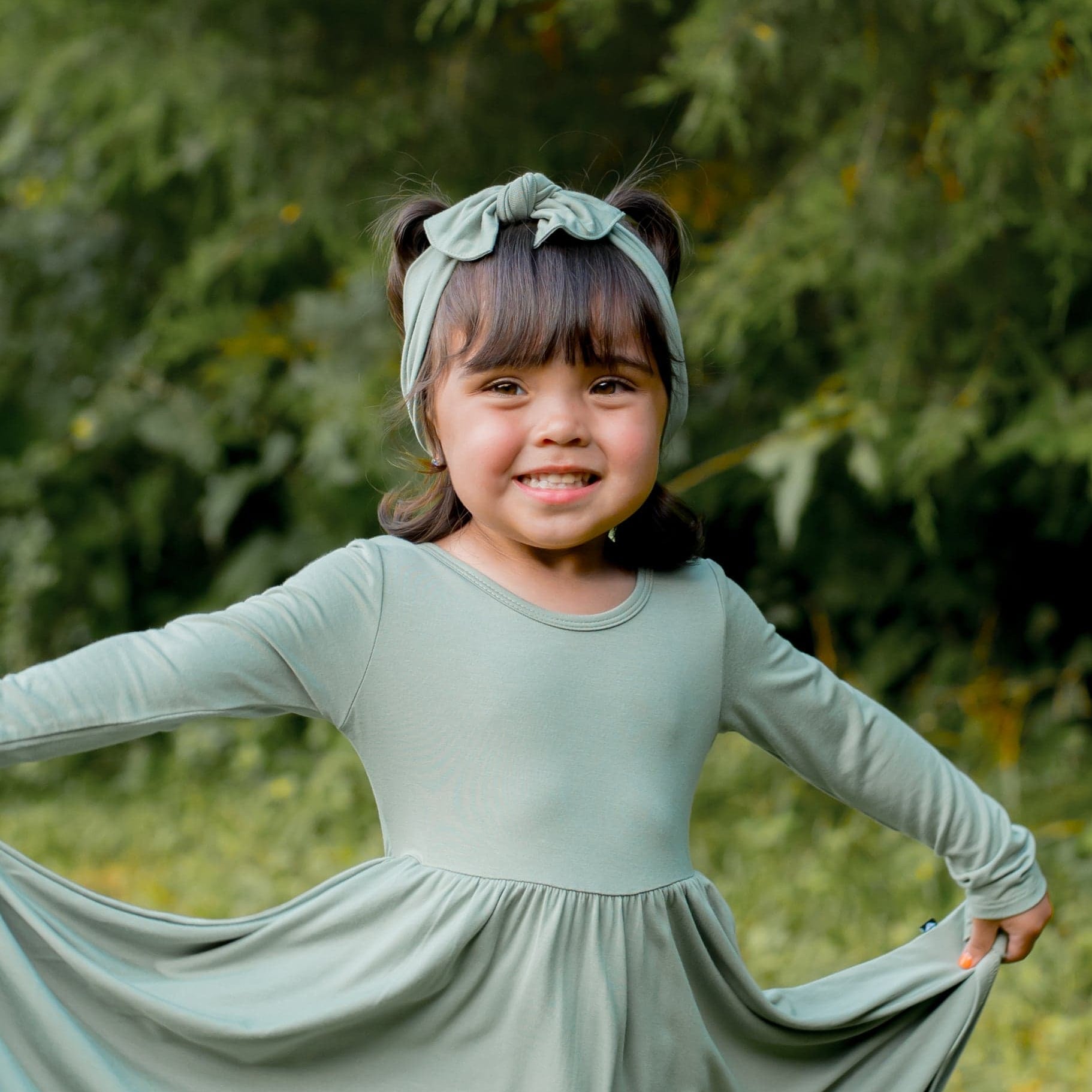 Young girl wearing the Knotted bow headband in Thyme paired with a matching long sleeve dress