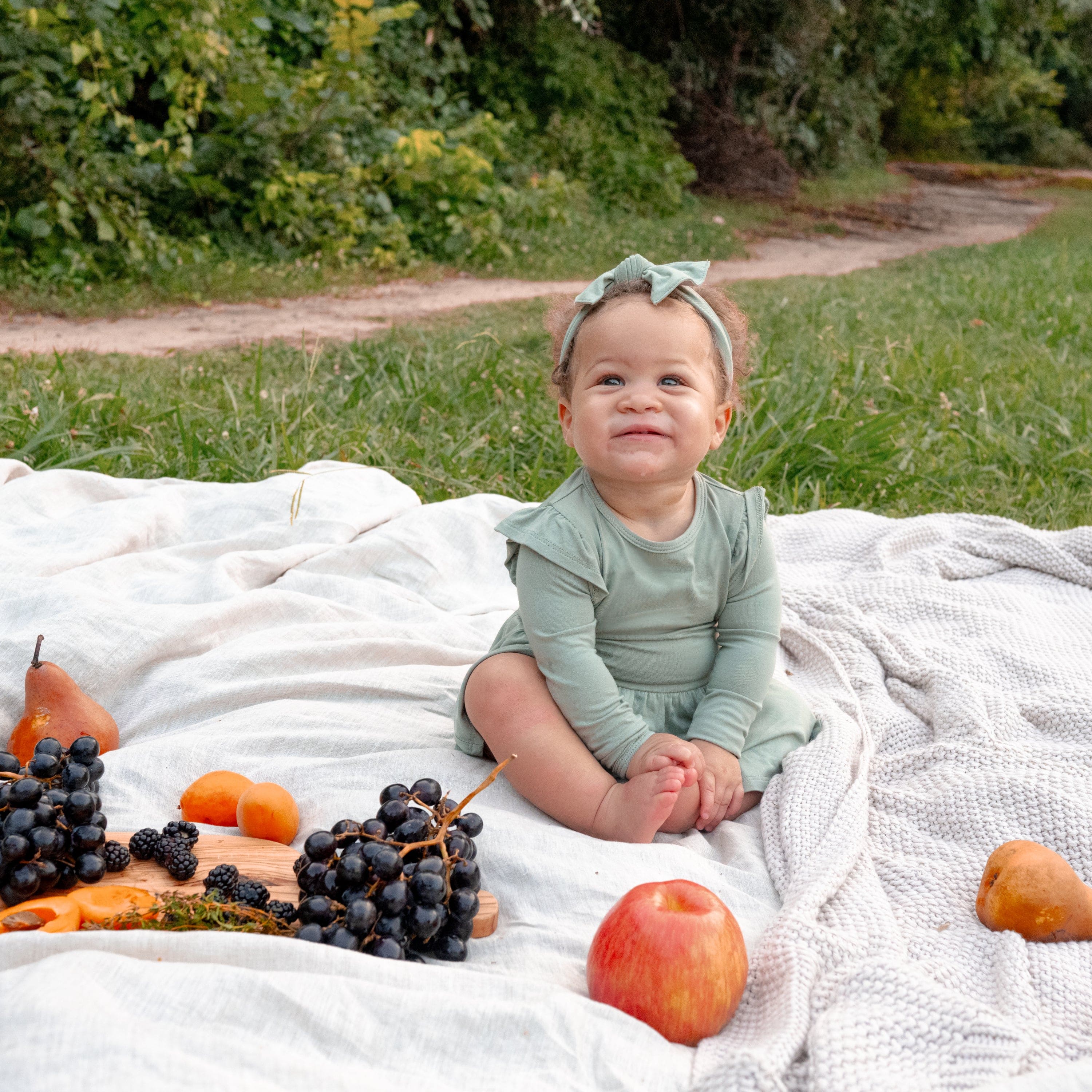 Infant wearing Kyte Baby Twirl Bodysuit Dress in Thyme