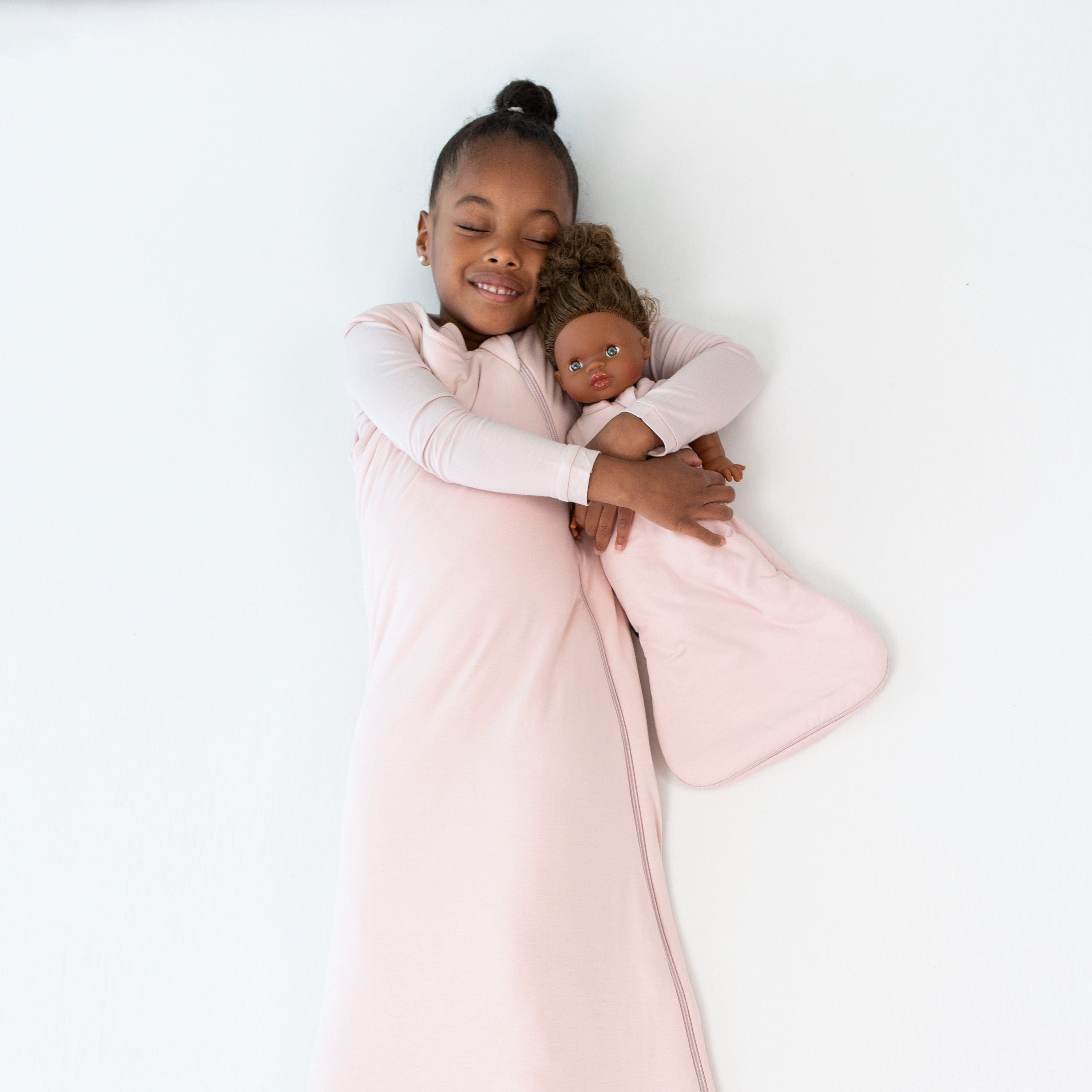 Toddler and Doll in Kyte Baby Matching Sleep Bags in Blush