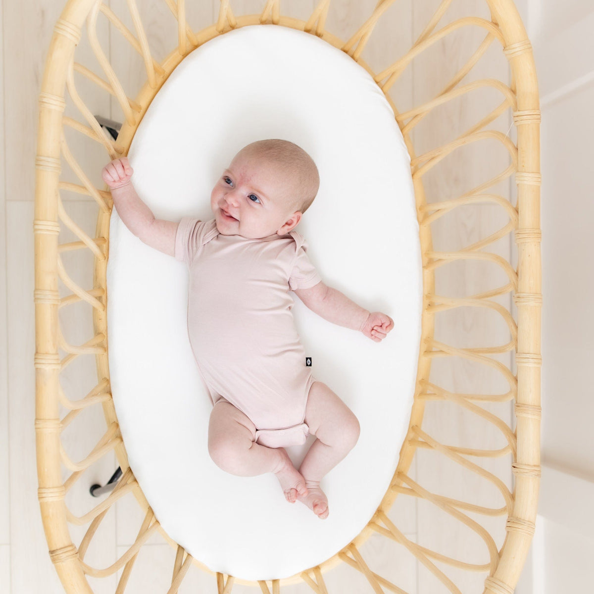 Baby laying on Kyte Baby Oval Bassinet Sheet in Cloud