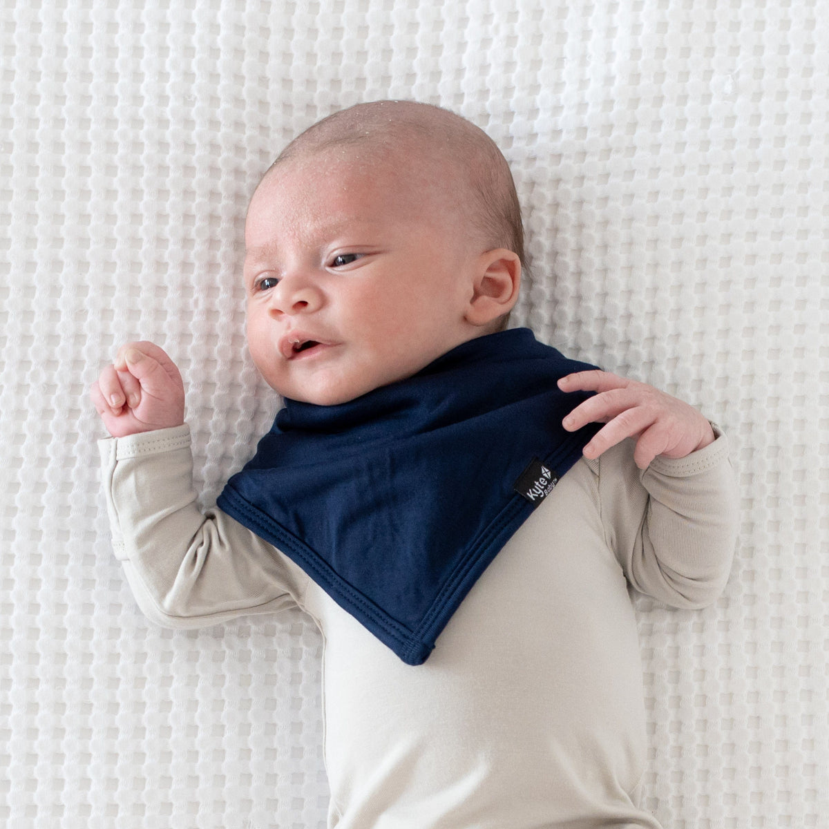 Infant wearing Kyte Baby Bib in Navy blue