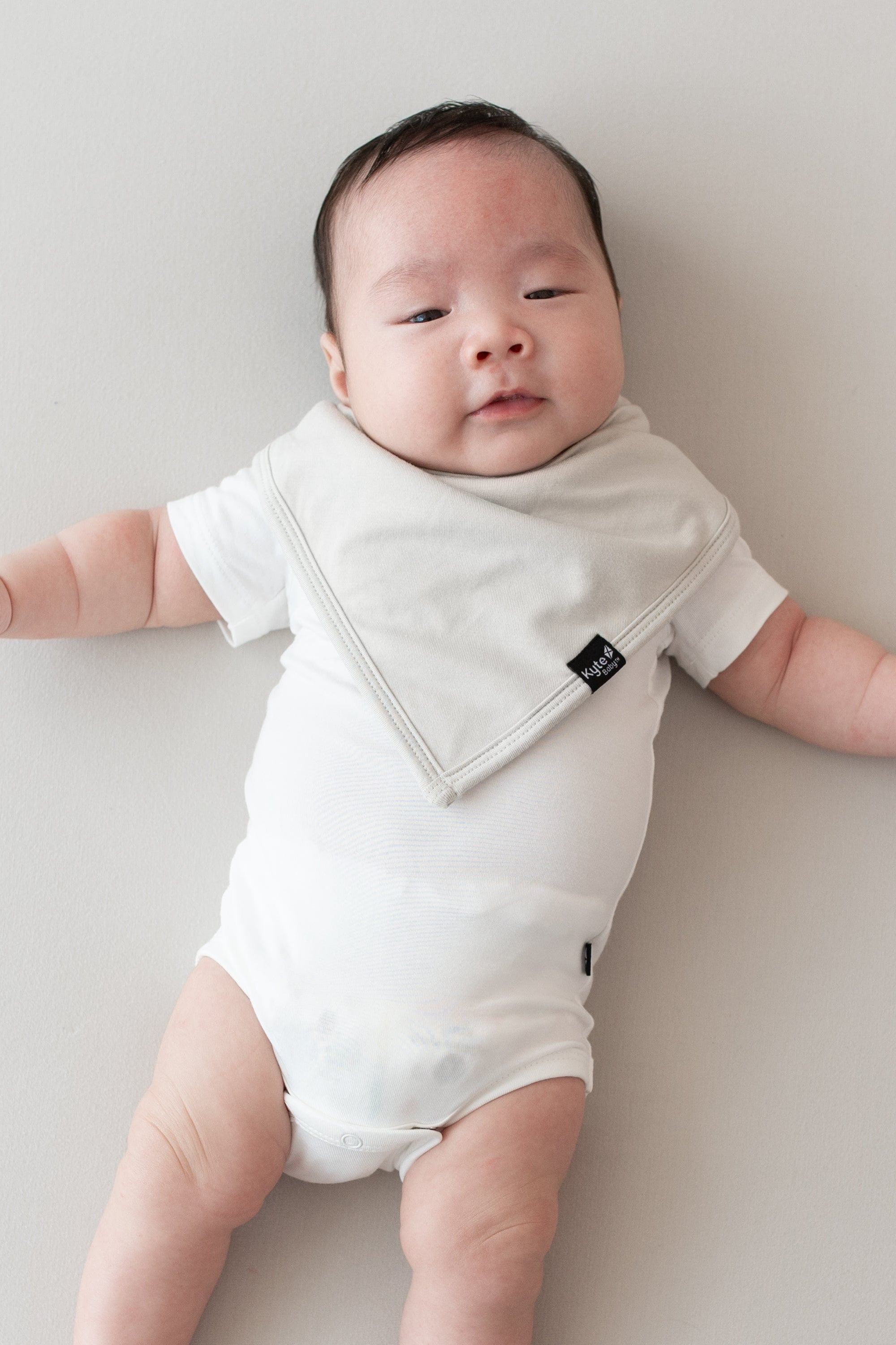 Baby wearing a Bib in Oat and Short Sleeve Bodysuit in Cloud