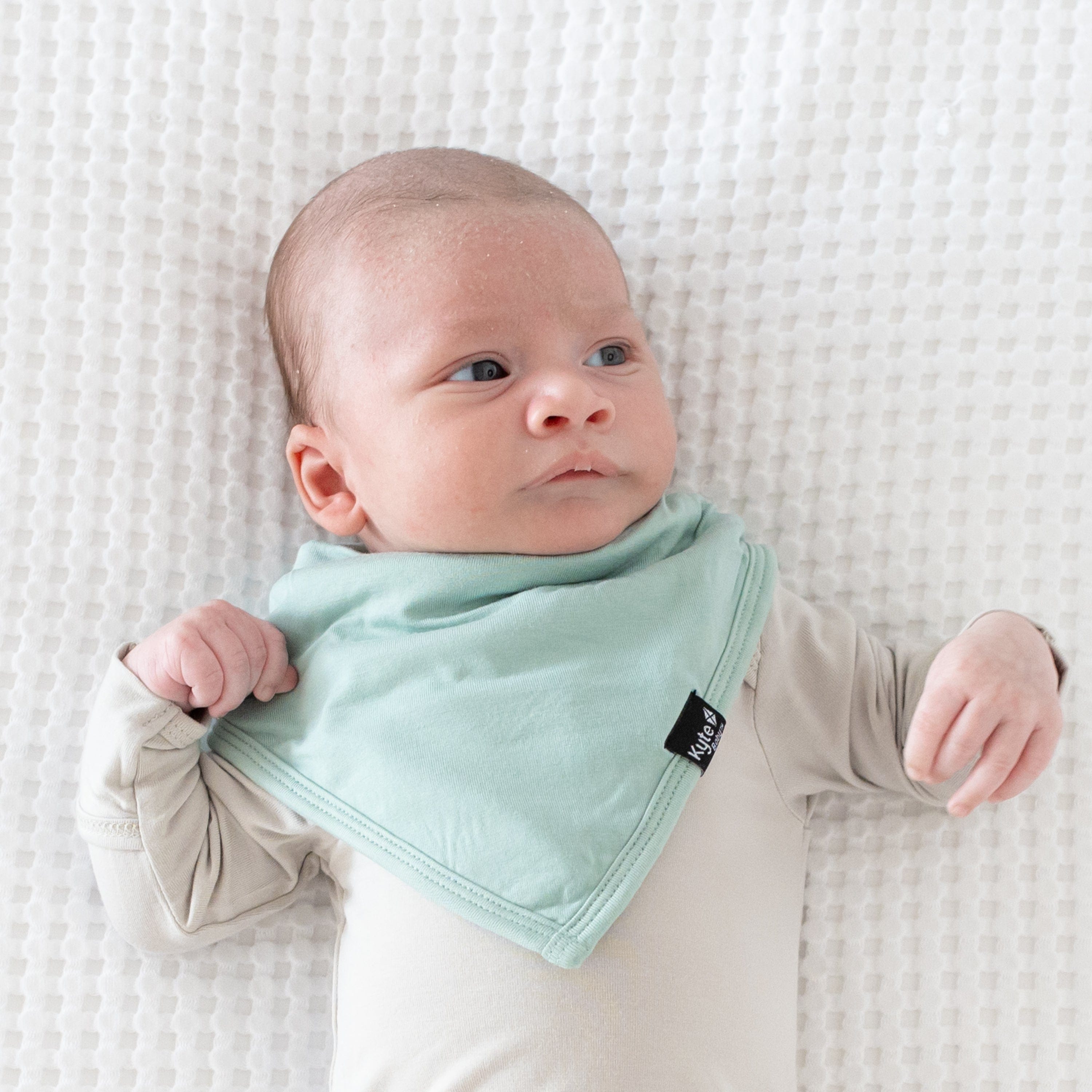 Infant wearing Kyte Baby Bib in Sage green