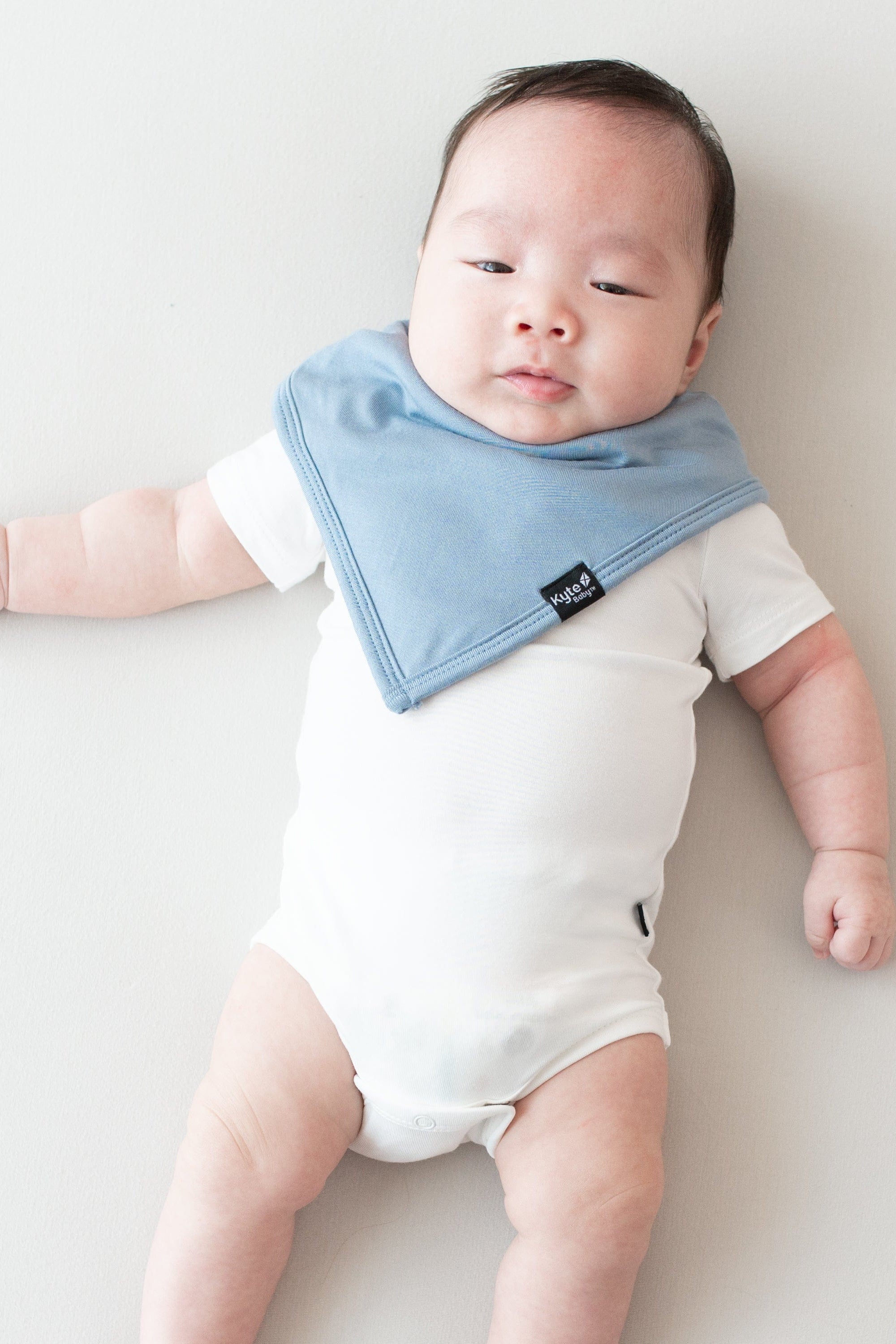 Infant modeling a Kyte Baby Bib in Slate and Short Sleeve Bodysuit in Cloud